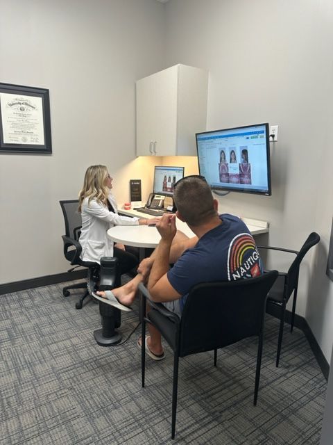 a man is sitting at a table talking to a woman in a dental office .