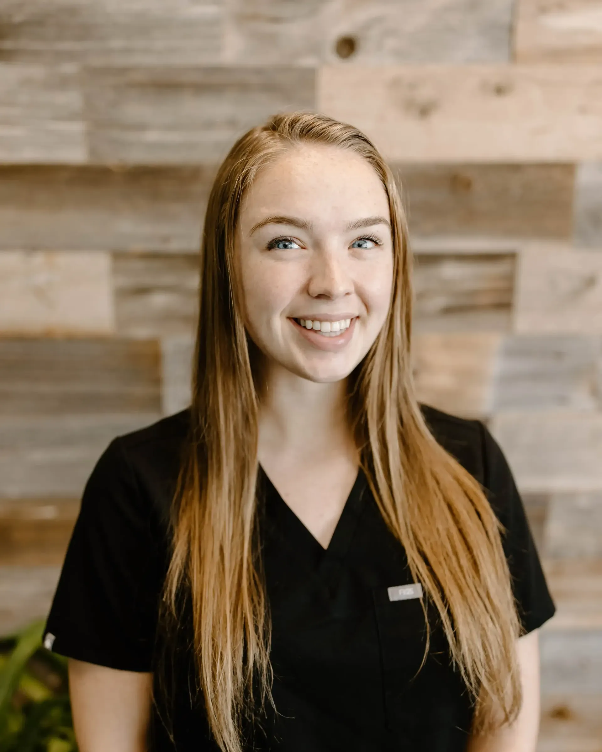 a smiling woman wearing a black scrub top with a name tag that says ' amanda ' on it