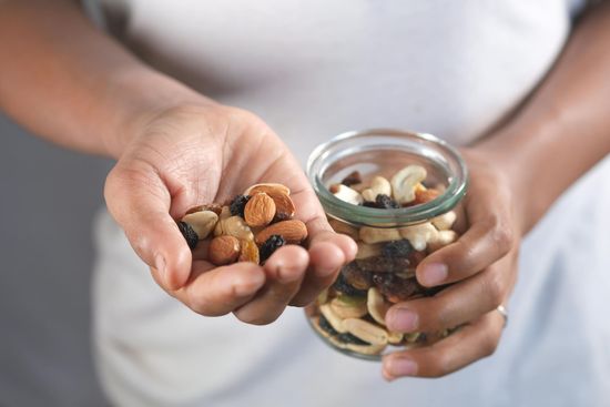 Hands holding coins and a glass jar of mixed coins against a white shirt backdrop