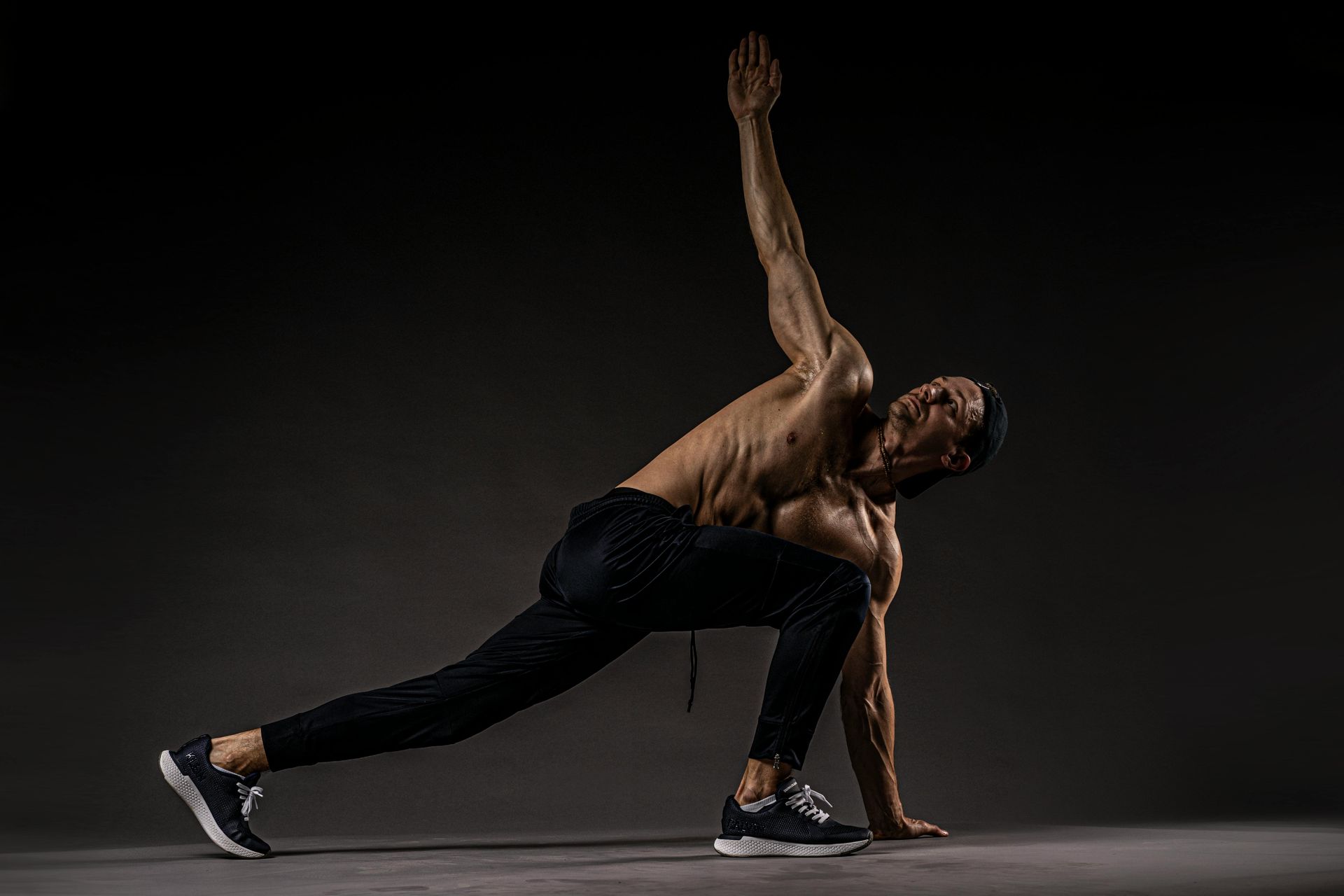 Athlete in a low lunge stretch against a dark studio background
