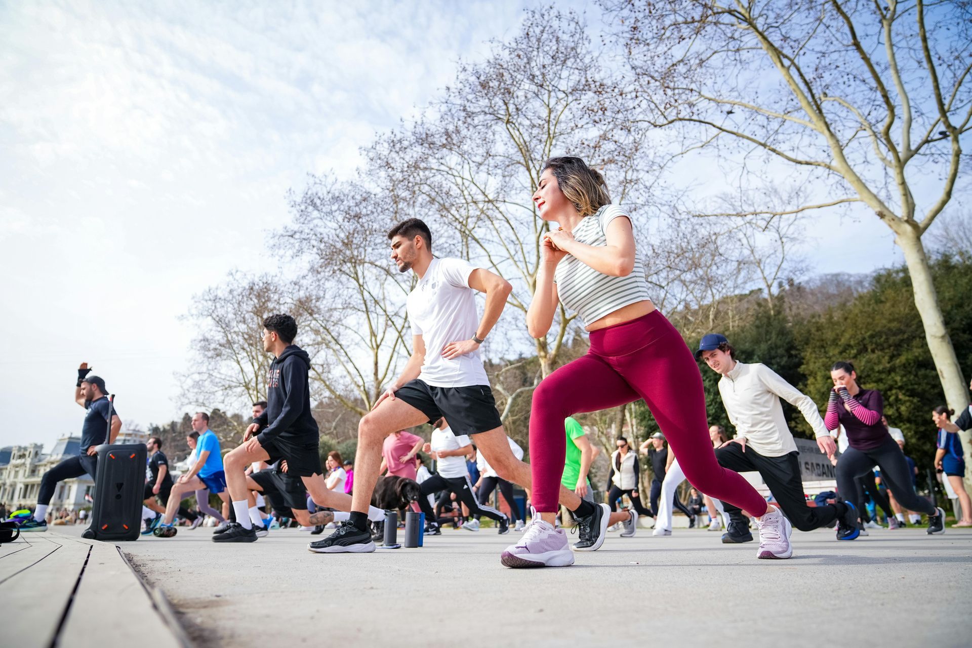 Group exercising outdoors in a park, with people doing lunges on a sunny day.