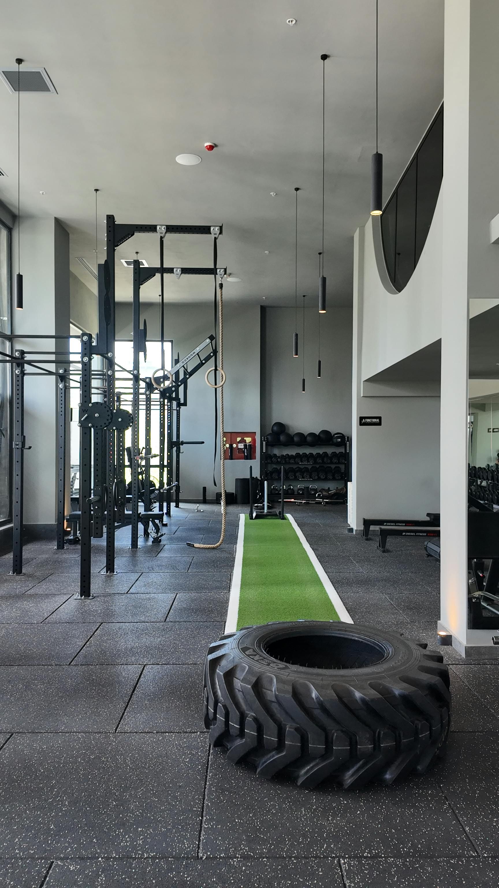Indoor gym with turf lane, battle ropes, weight racks, and a large tire on the floor