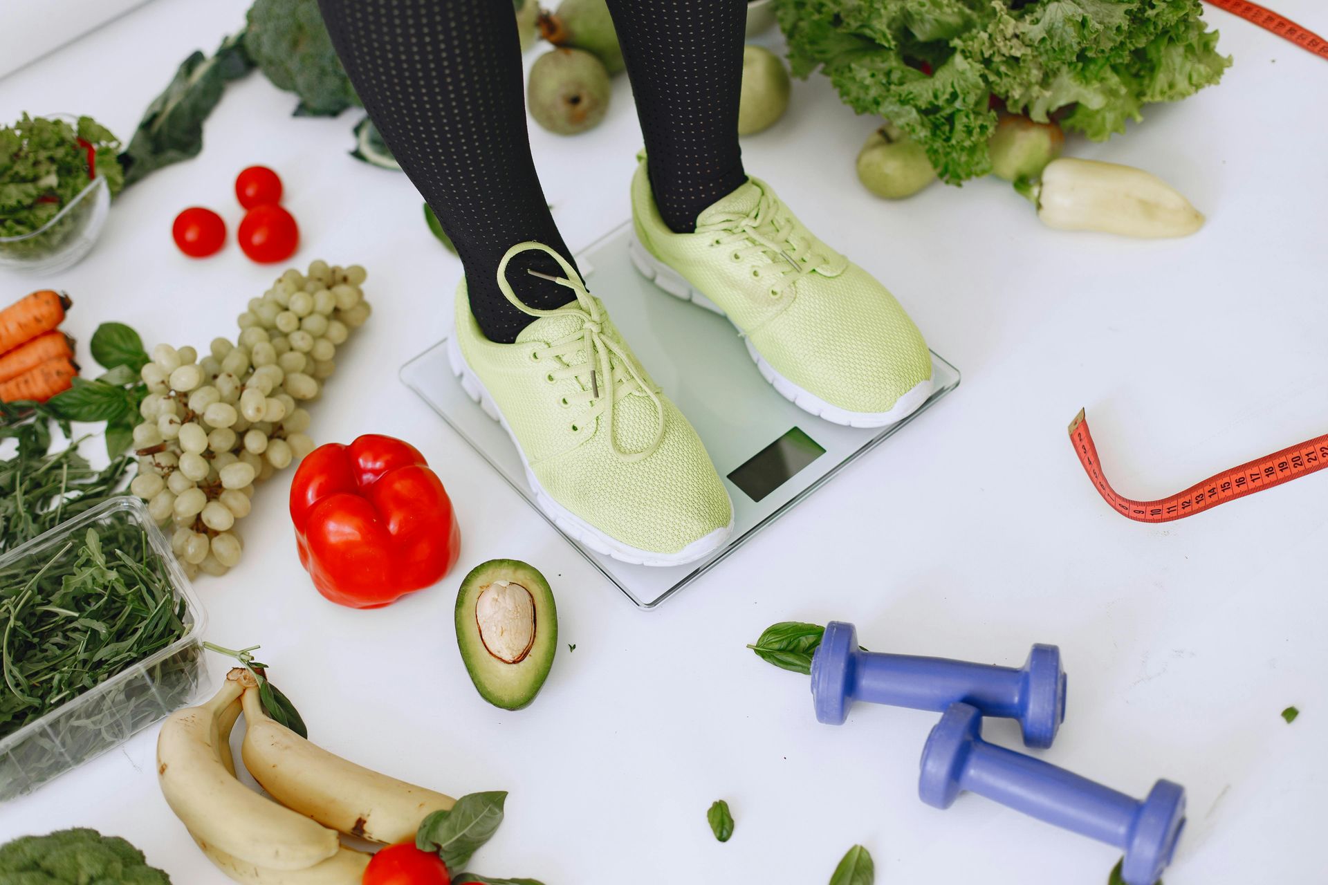 Athletic shoes amid fresh vegetables and dumbbells, suggesting a healthy lifestyle concept