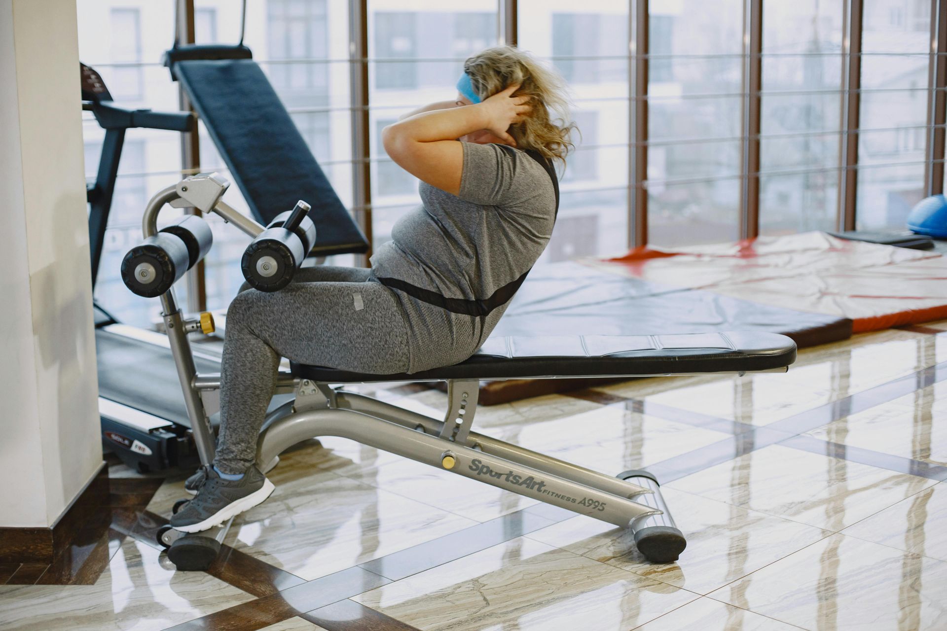 Person doing sit-ups on a gym bench in a bright fitness room
