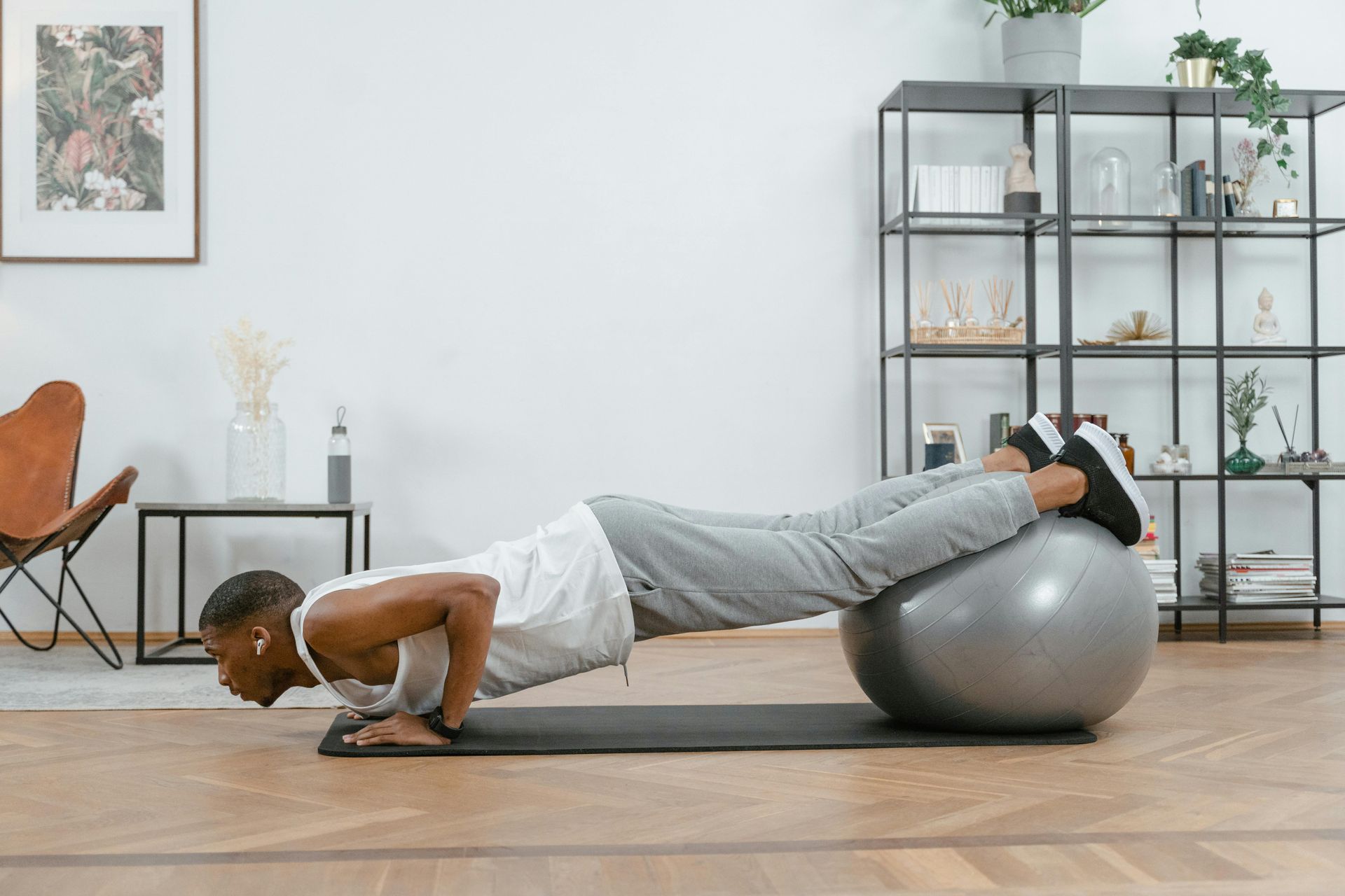 Person doing a push-up with feet on a stability ball in a bright living room.