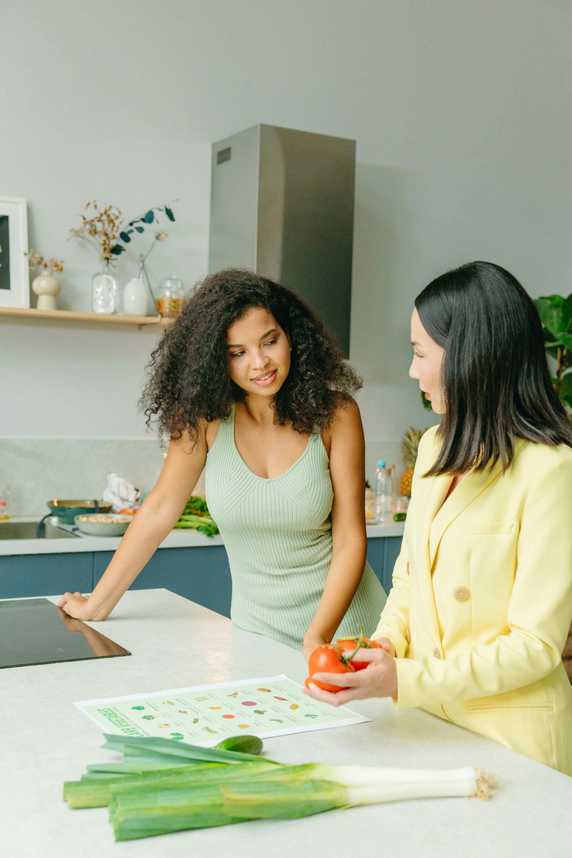 Two people preparing vegetables in a bright kitchen, with green onions on the counter.