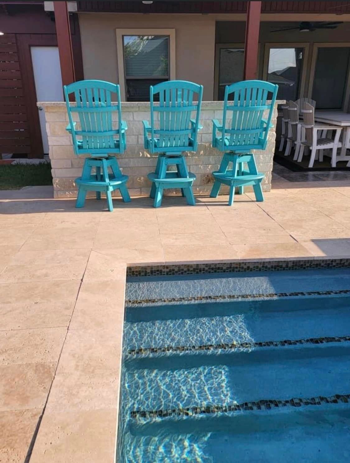 A row of blue chairs are sitting next to a swimming pool.