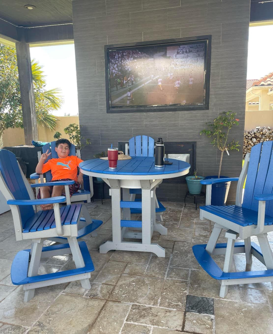 A boy is sitting at a table and chairs on a patio.