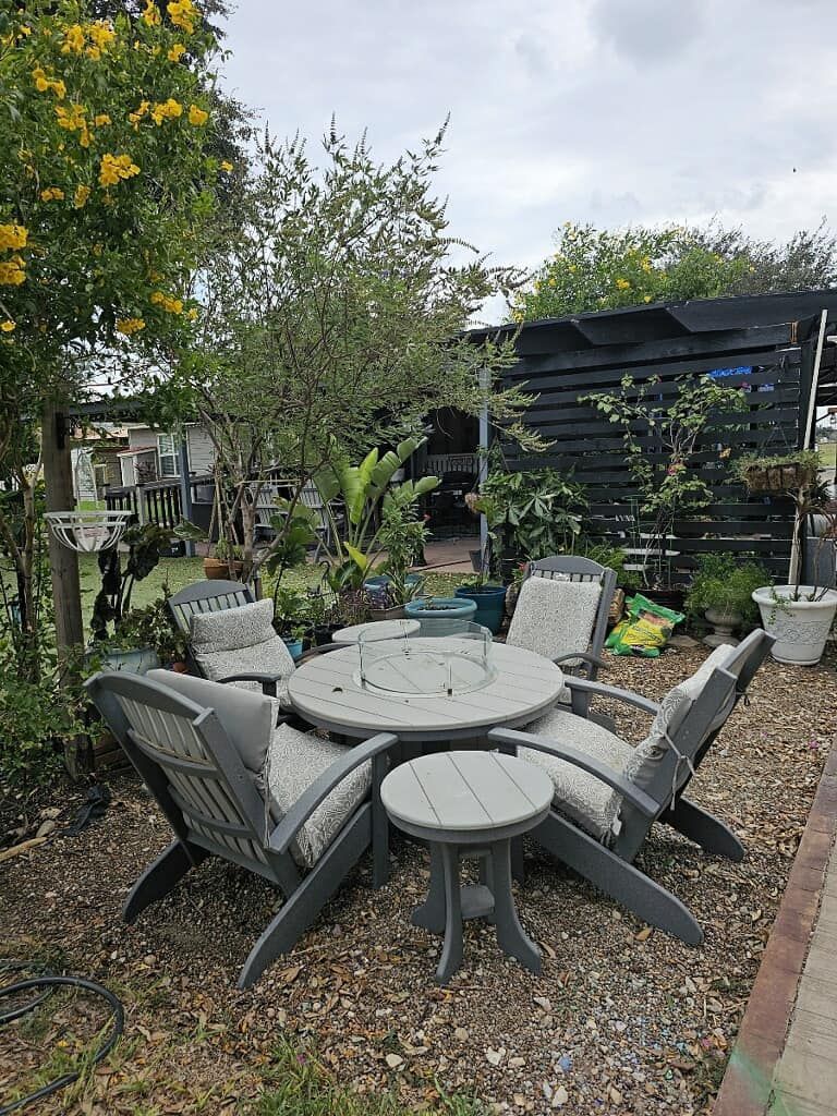 A table and chairs are sitting in a gravel area in a garden.