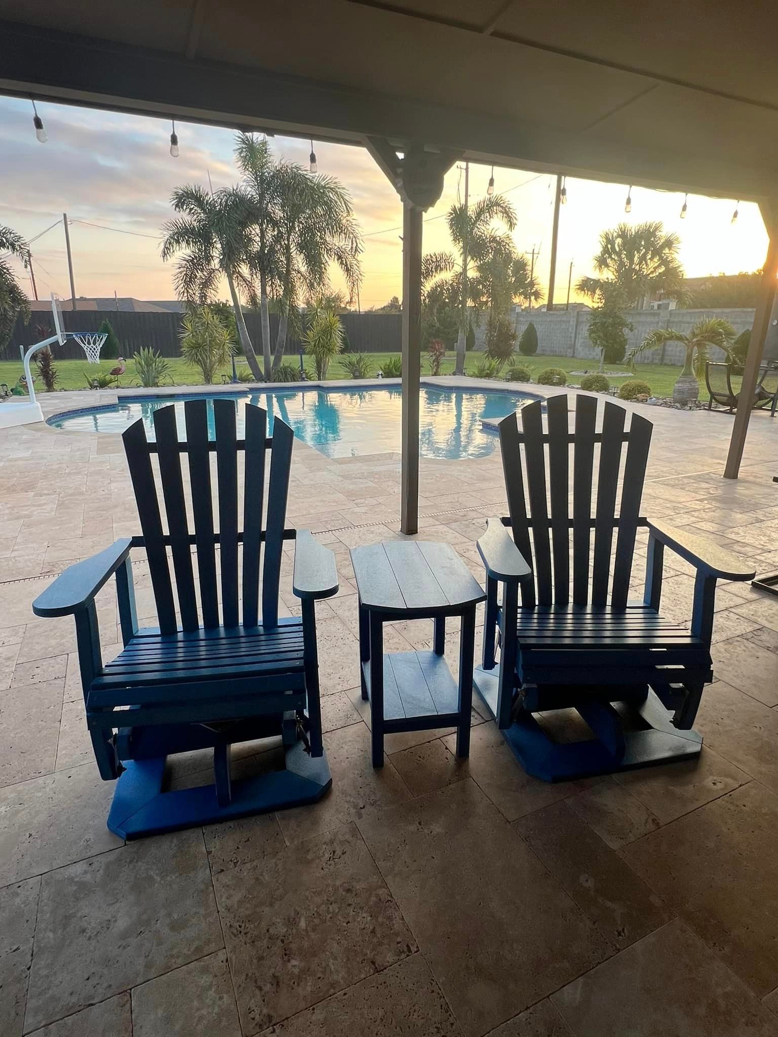 Two blue adirondack chairs are sitting on a patio next to a pool.