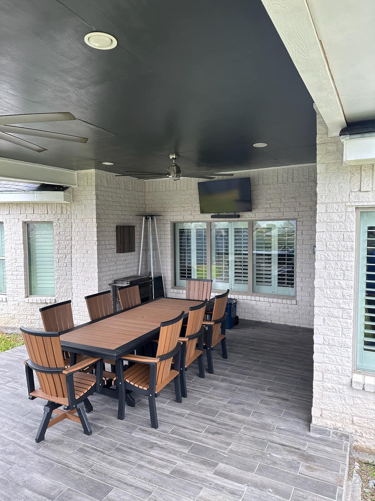A patio with a table and chairs under a black roof.