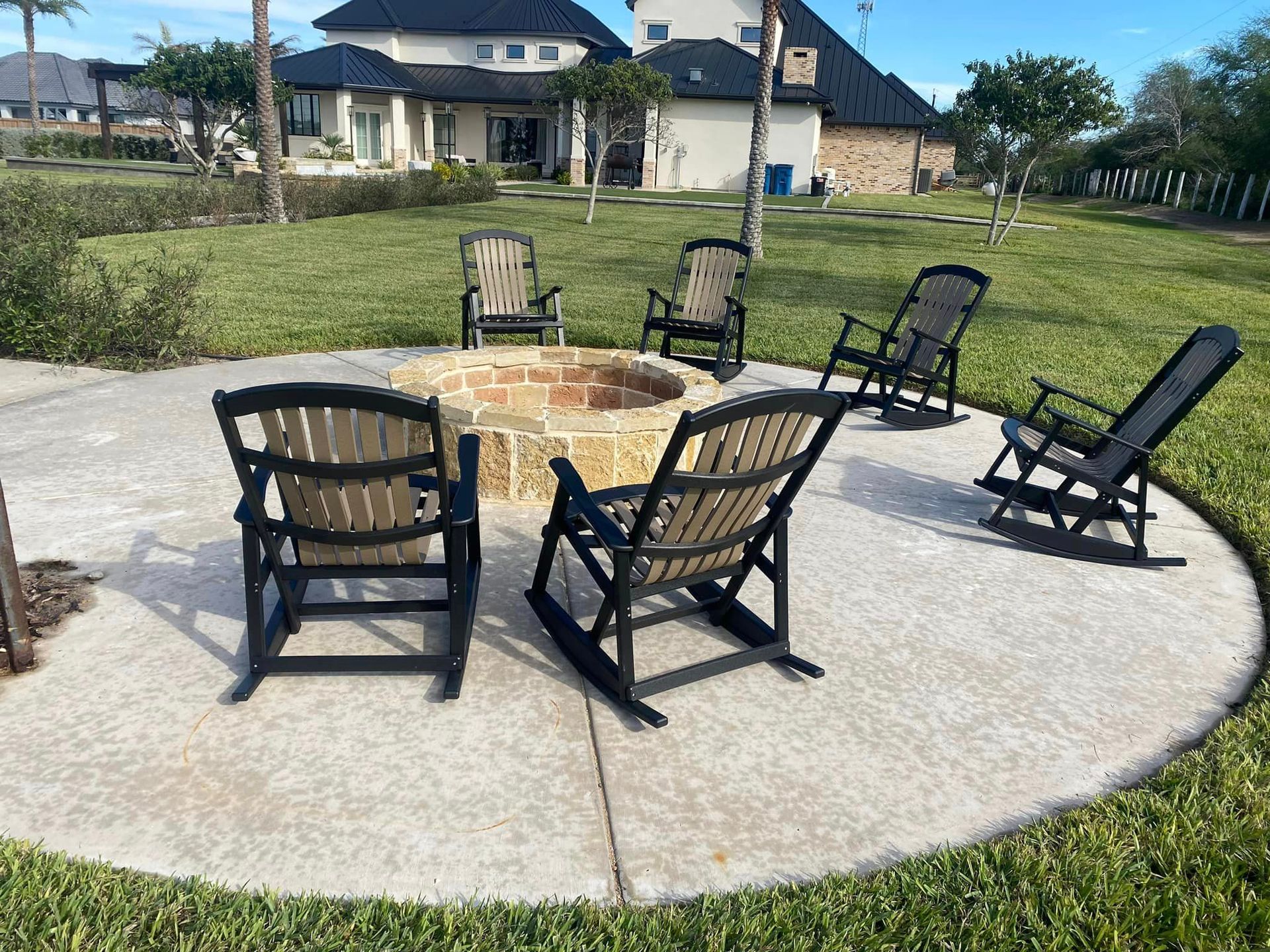 A group of rocking chairs are sitting around a fire pit.