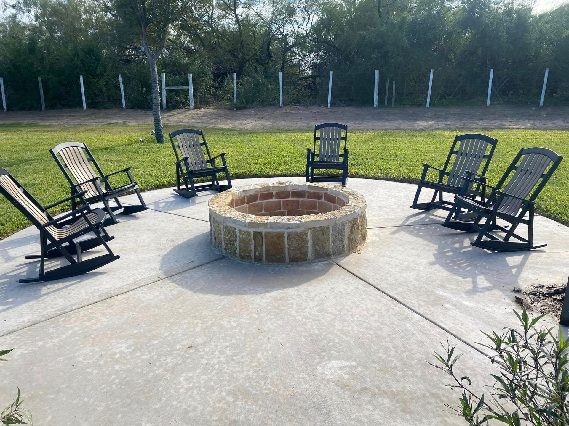 A group of rocking chairs are sitting around a fire pit.