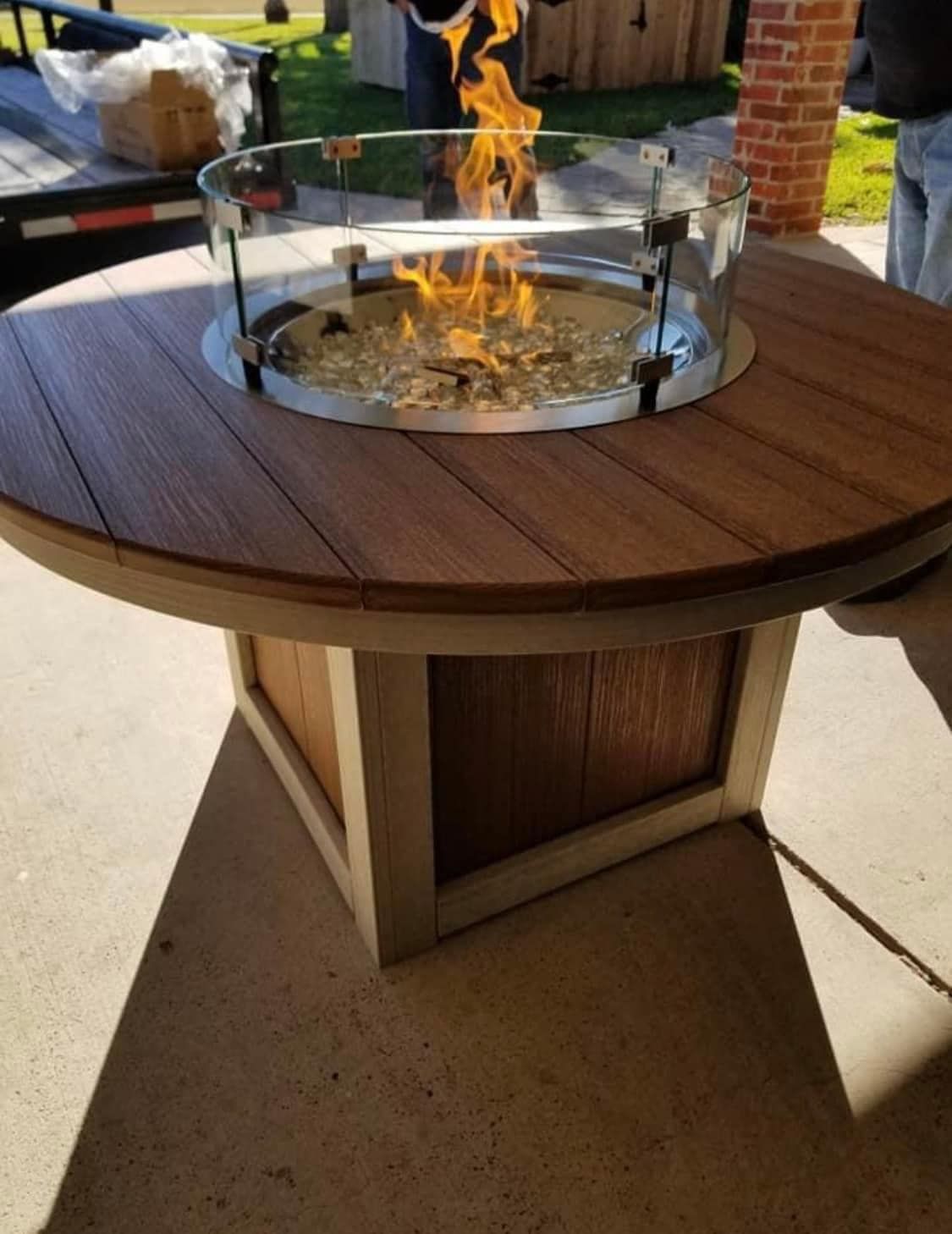 A round wooden table with a fire pit in the middle