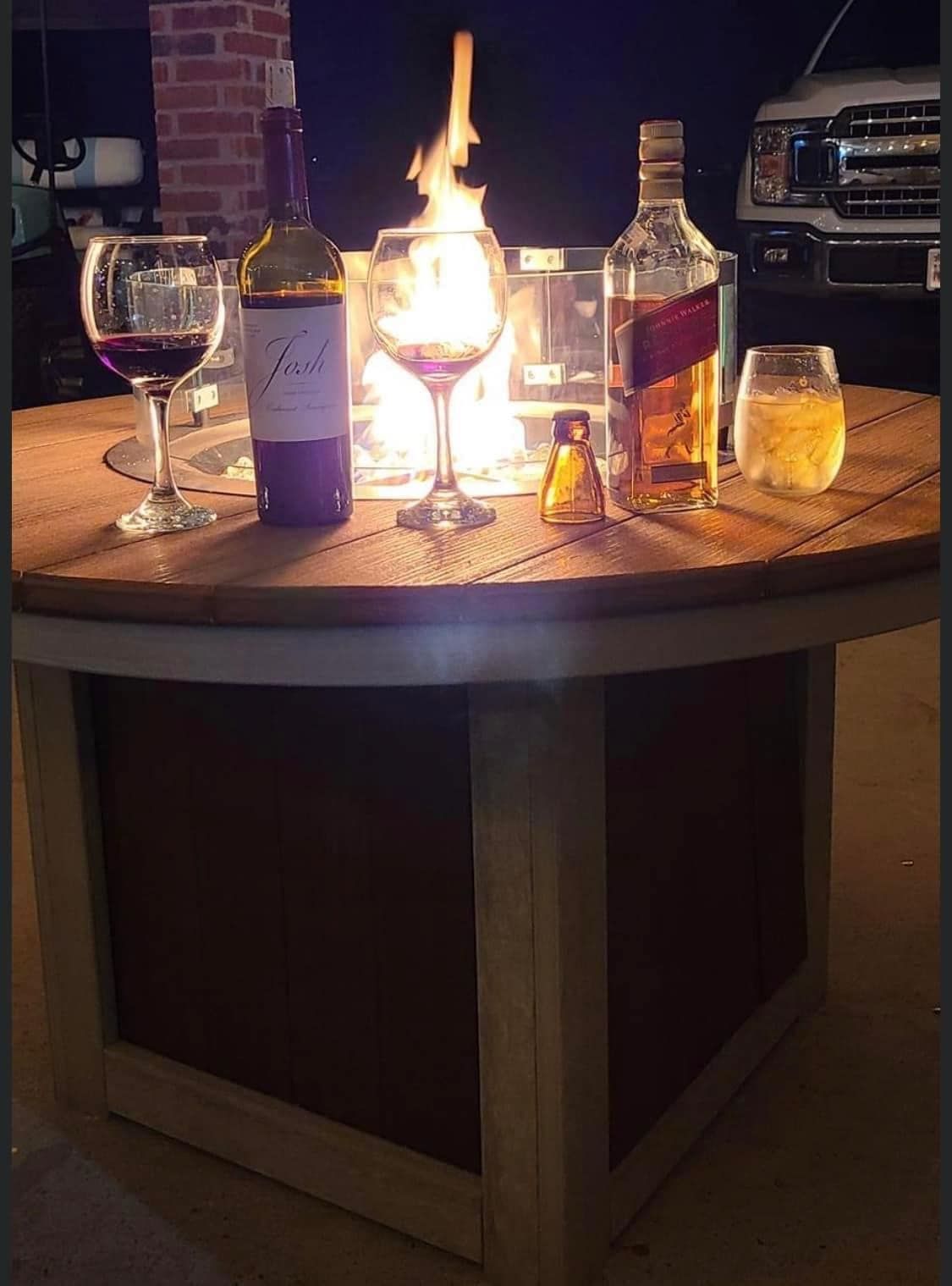 A bottle of johnnie walker sits on a table next to two glasses of wine