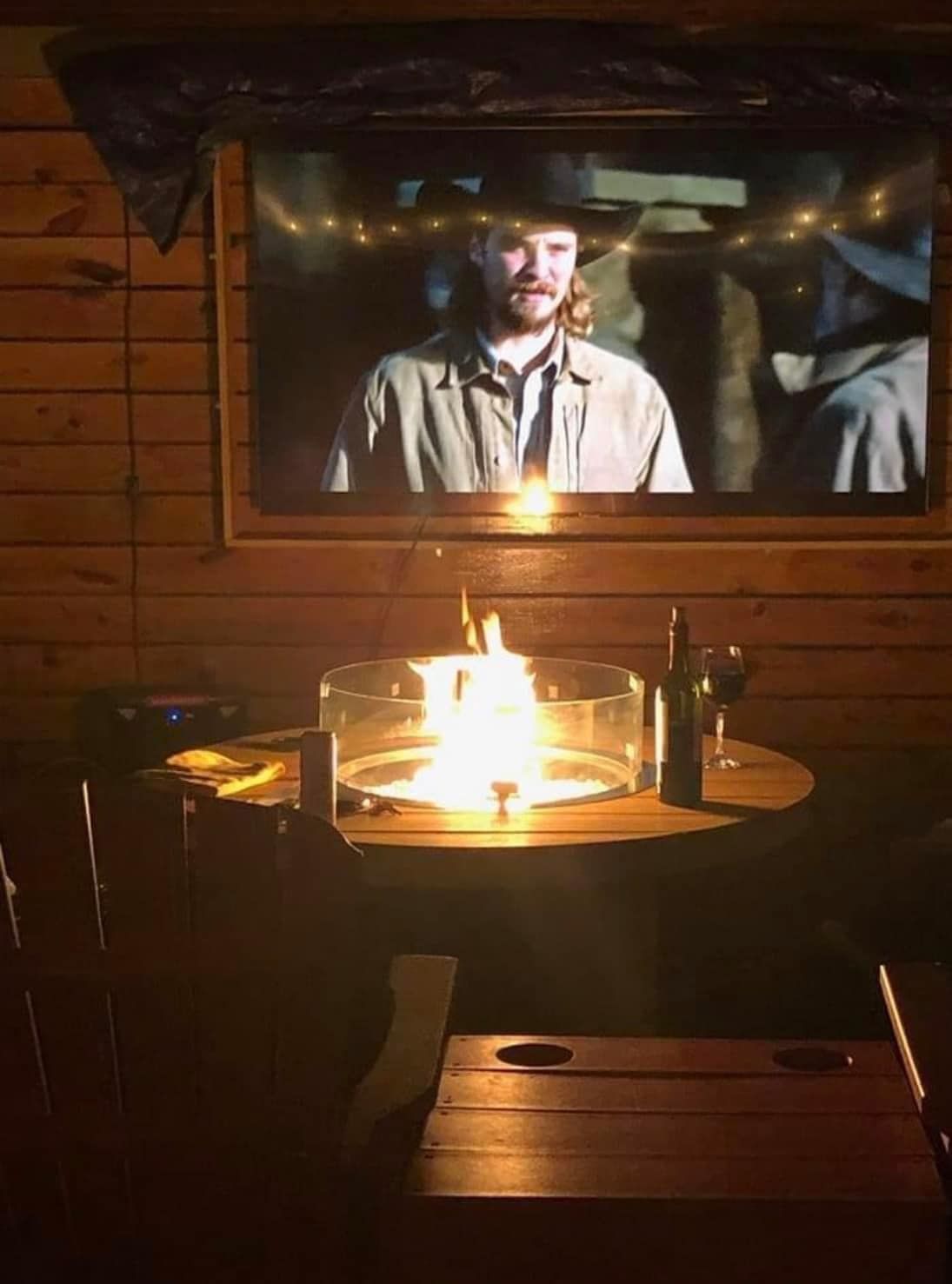 A man is sitting at a table watching a movie on a television.