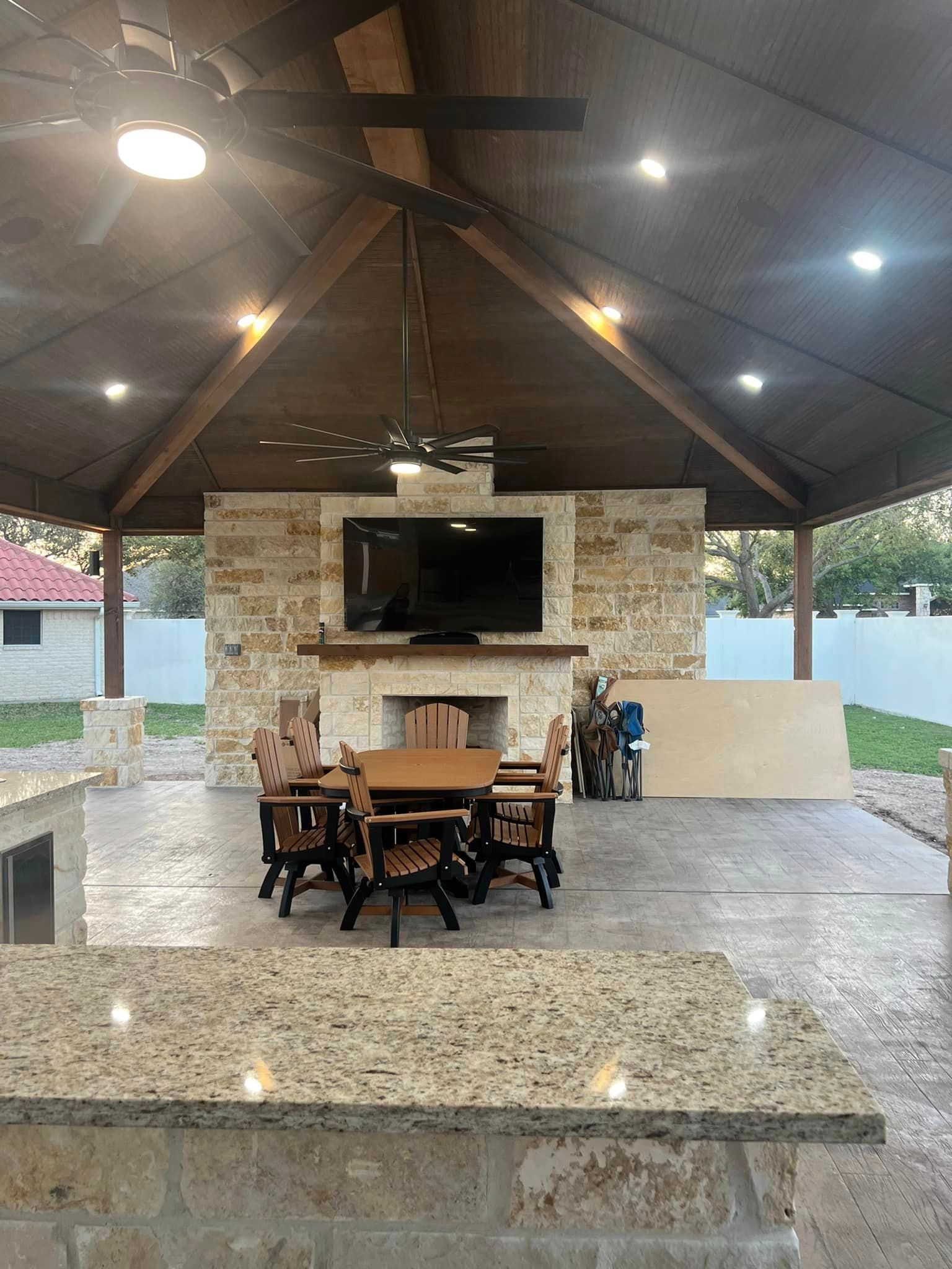 A patio with a table , chairs , a fireplace and a television.