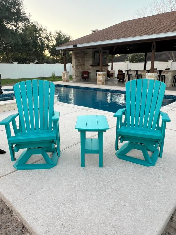 Two turquoise chairs and a table in front of a pool