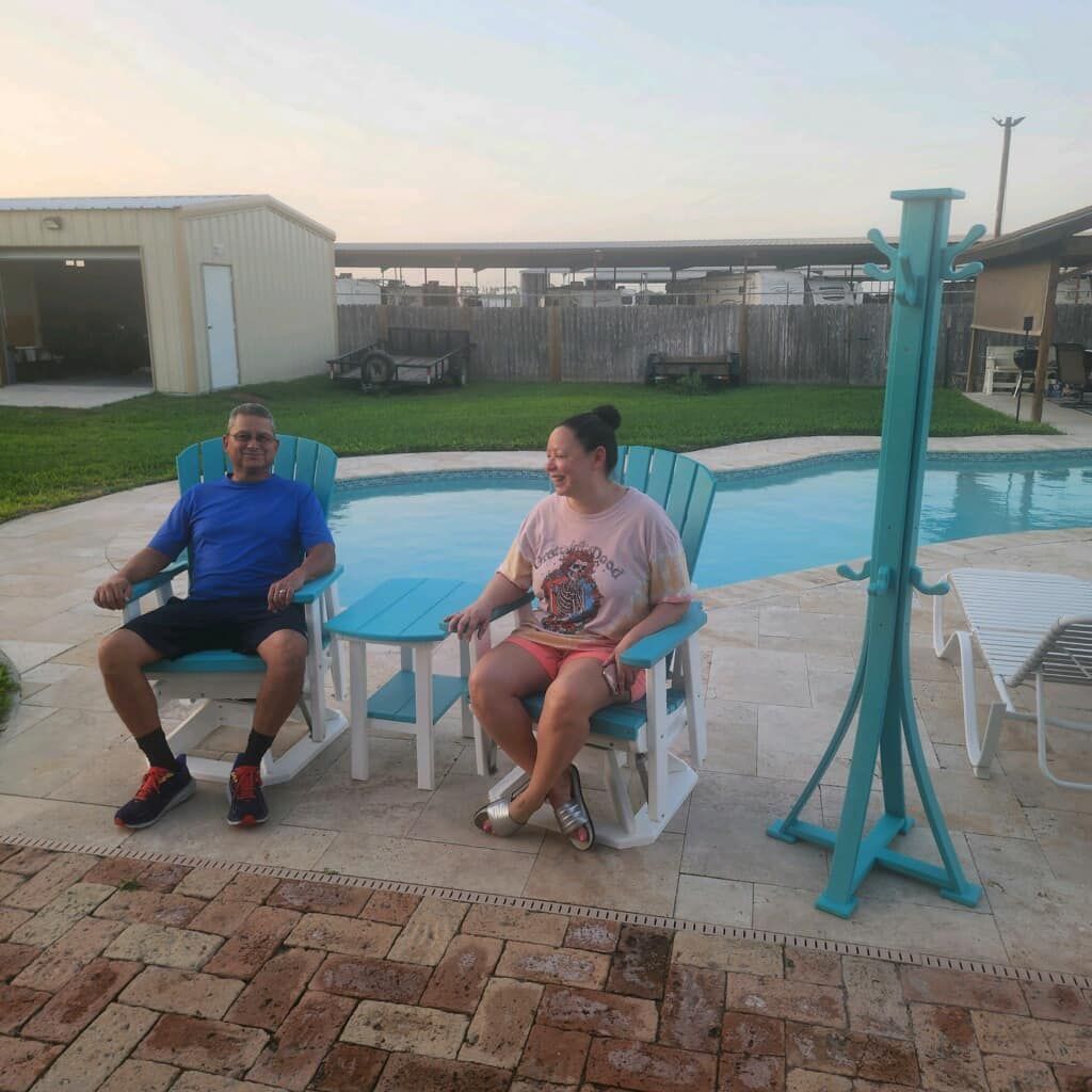 A man and a woman are sitting in rocking chairs near a pool.
