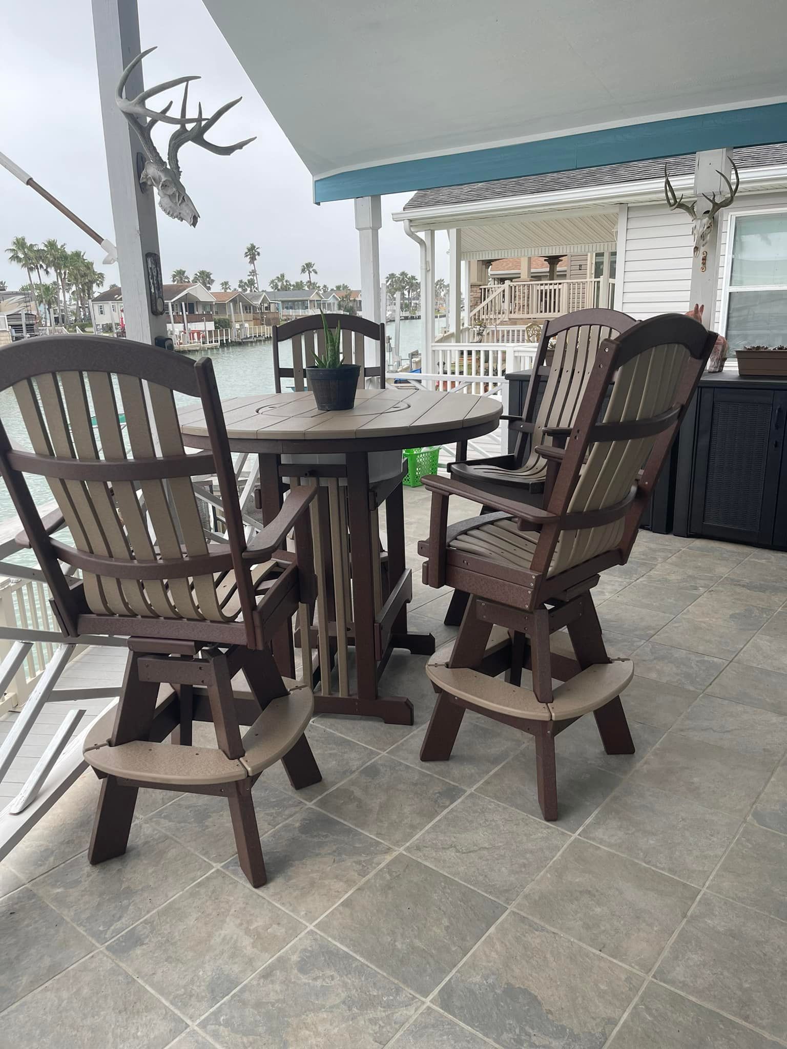 A table and chairs on a porch overlooking the water.