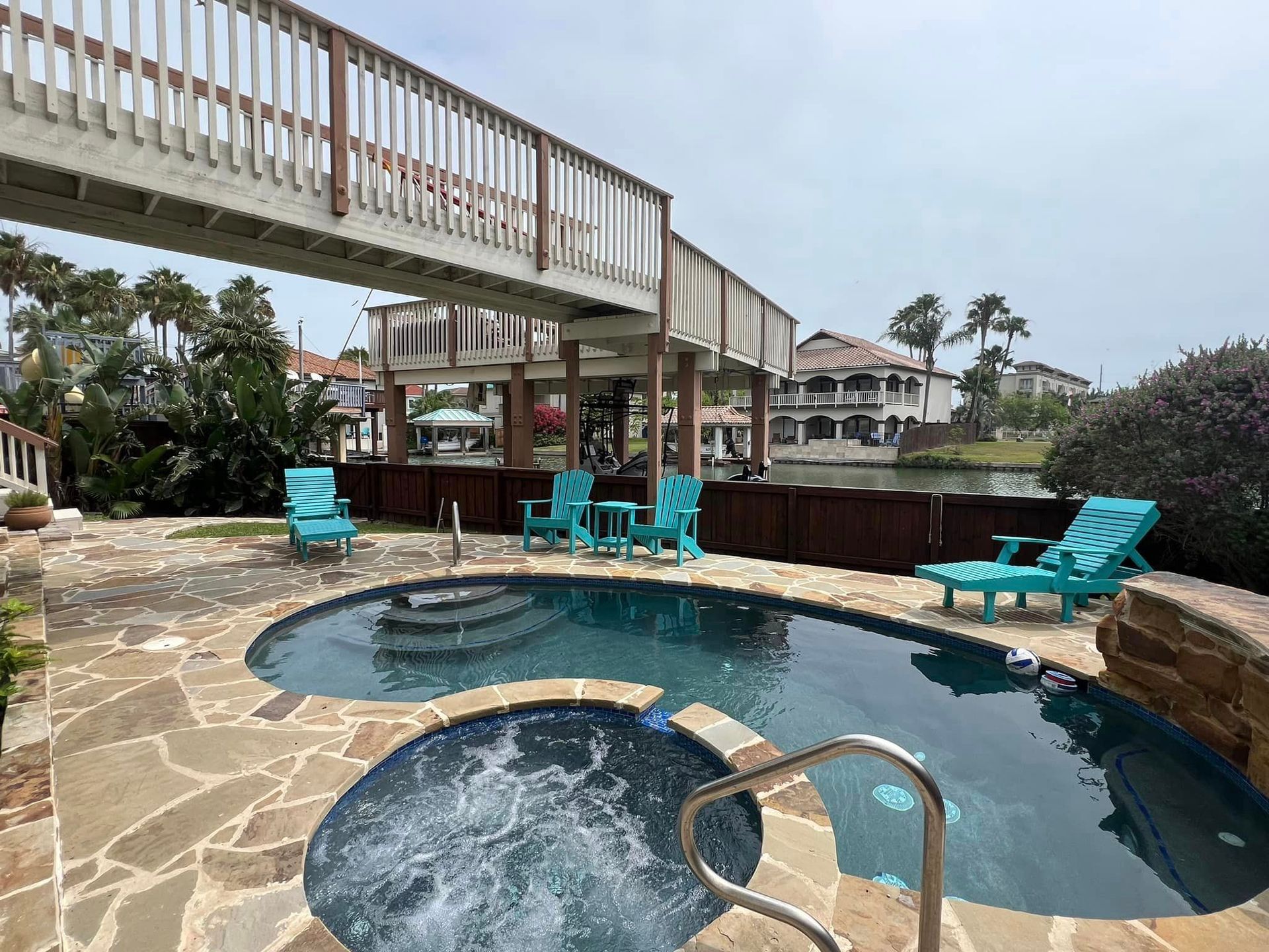A large swimming pool with a hot tub and a bridge over it.