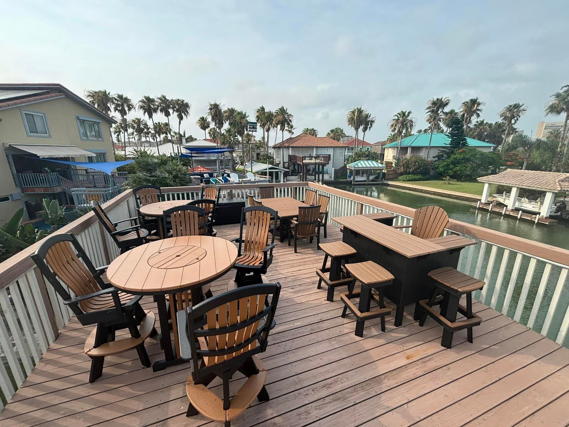 A deck with tables and chairs on it overlooking a body of water.