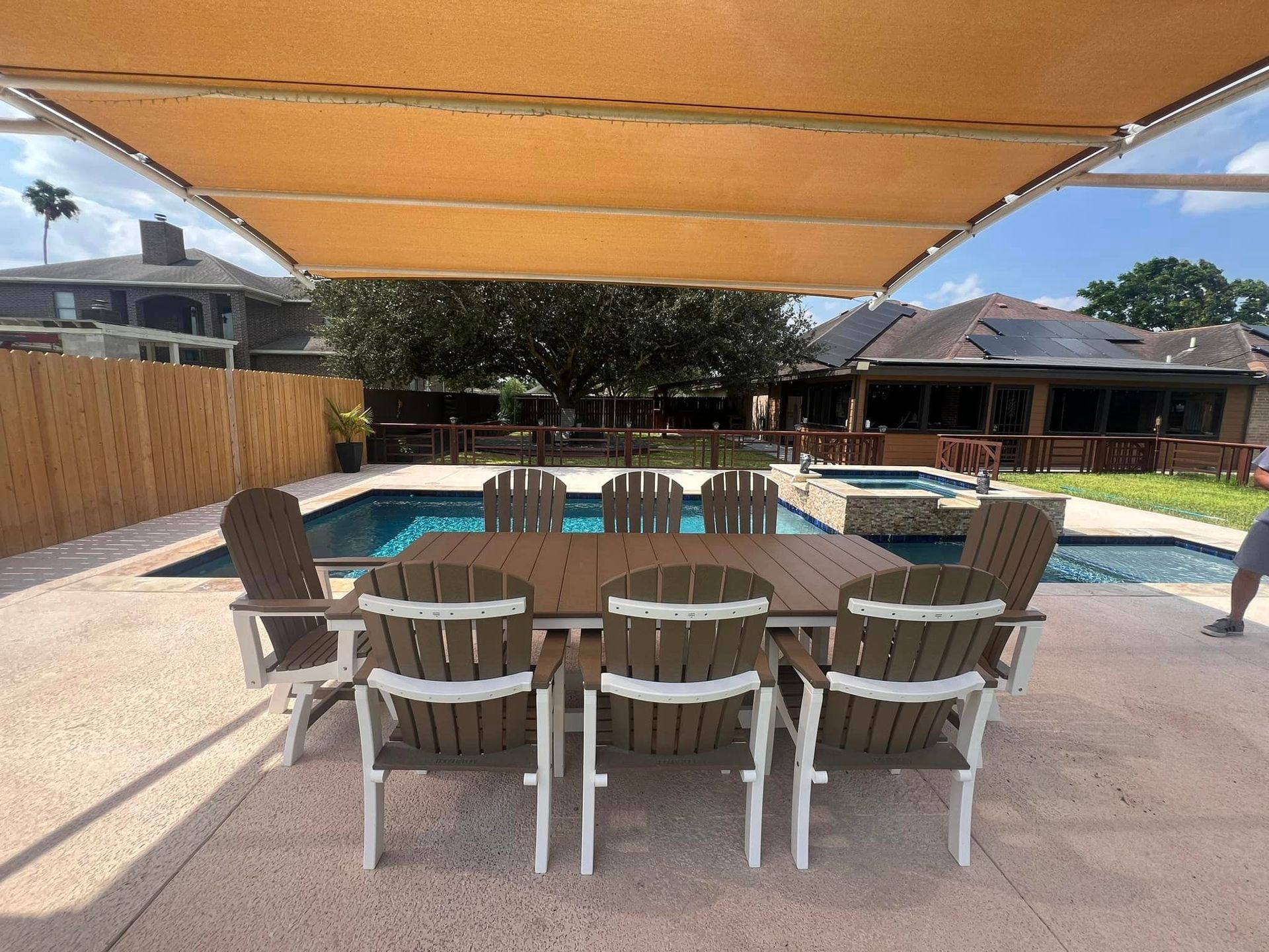 A table and chairs under a canopy next to a pool.