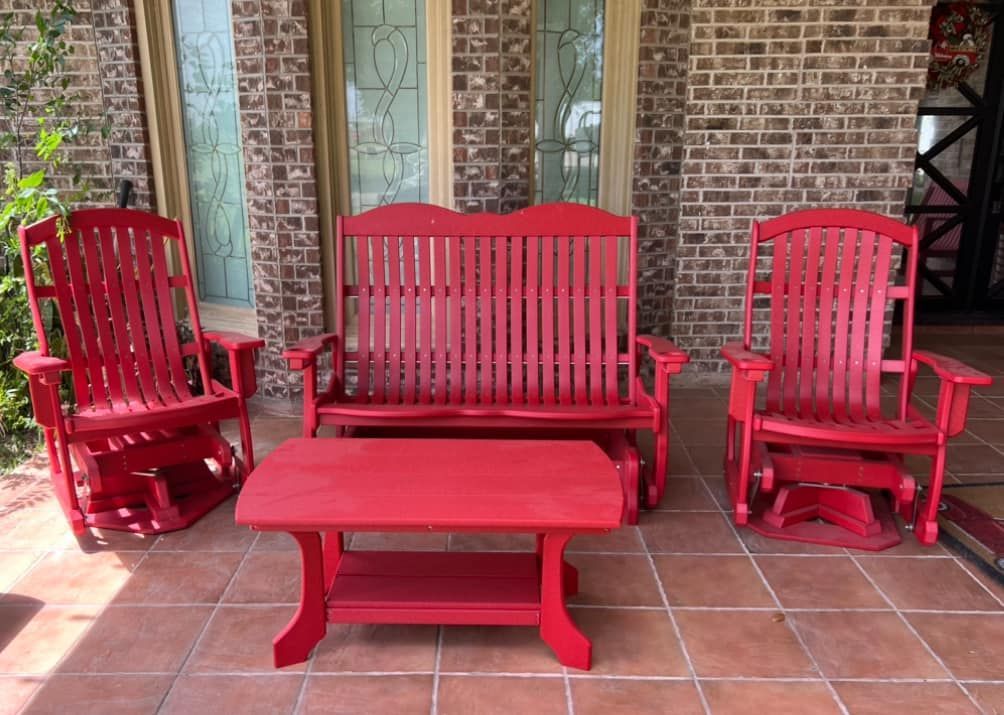 A red porch set with a bench , two rocking chairs , and a coffee table.