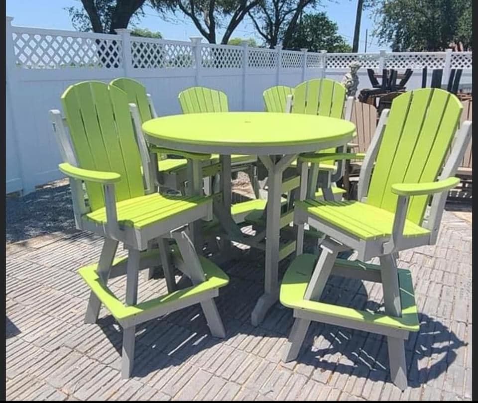 A table and chairs set on a patio with a white fence in the background