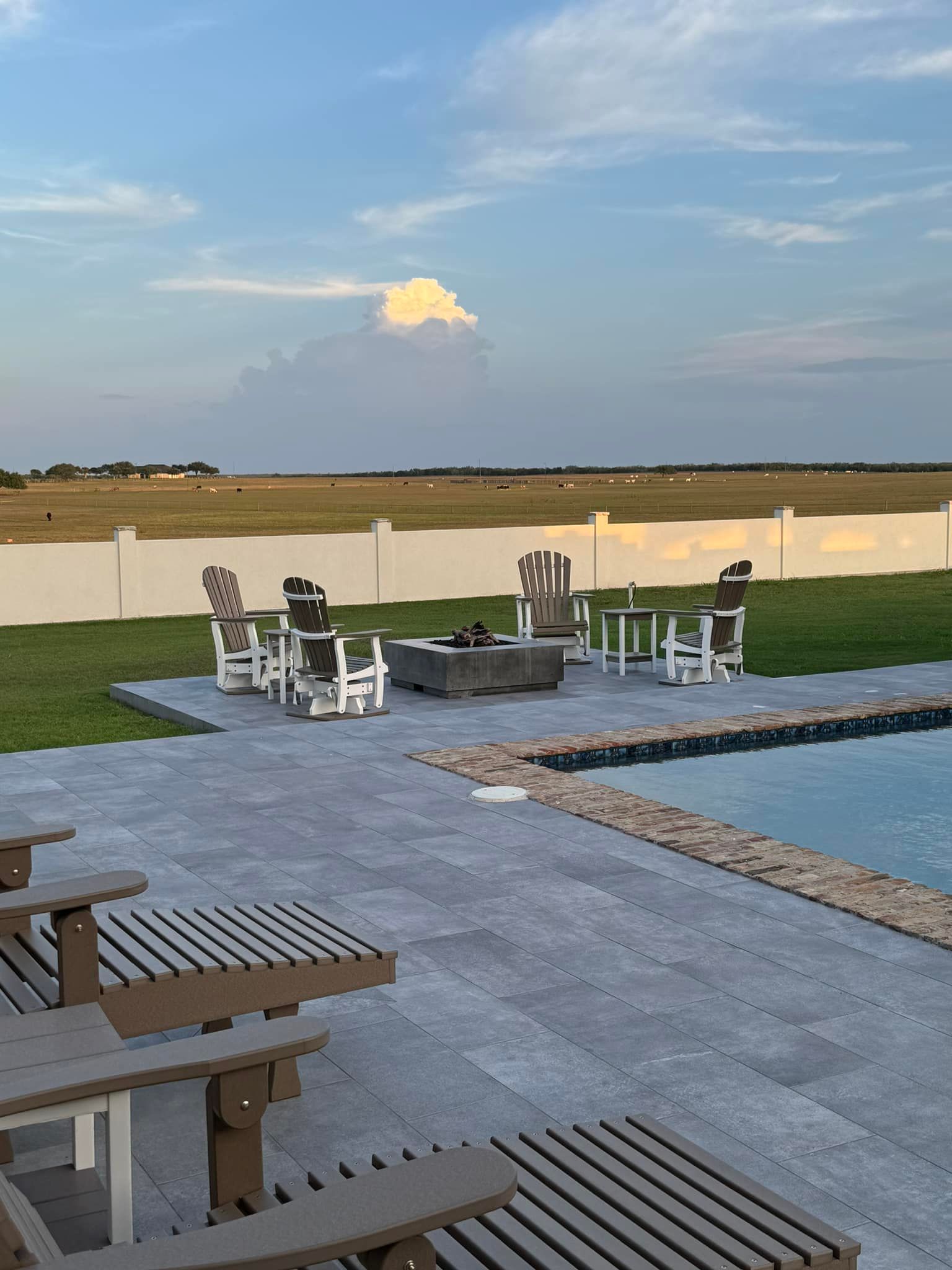 A patio with chairs and tables next to a swimming pool