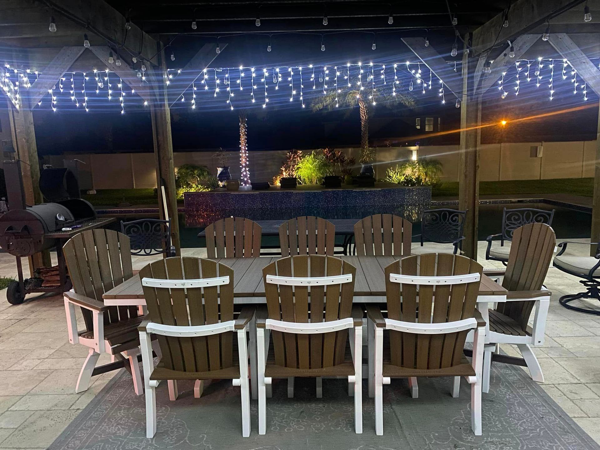 A patio table and chairs under a pergola at night.