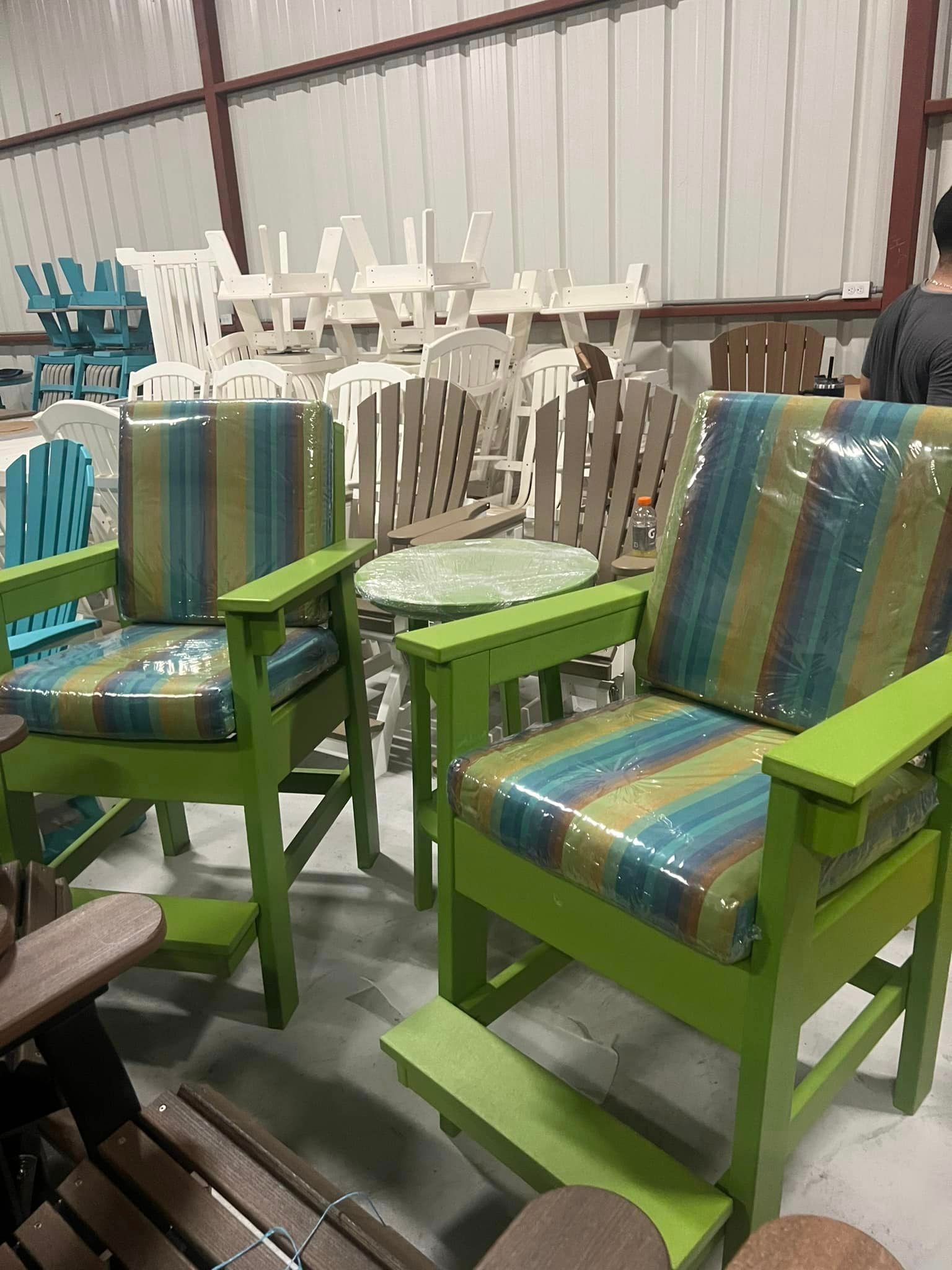A warehouse filled with green chairs and tables.