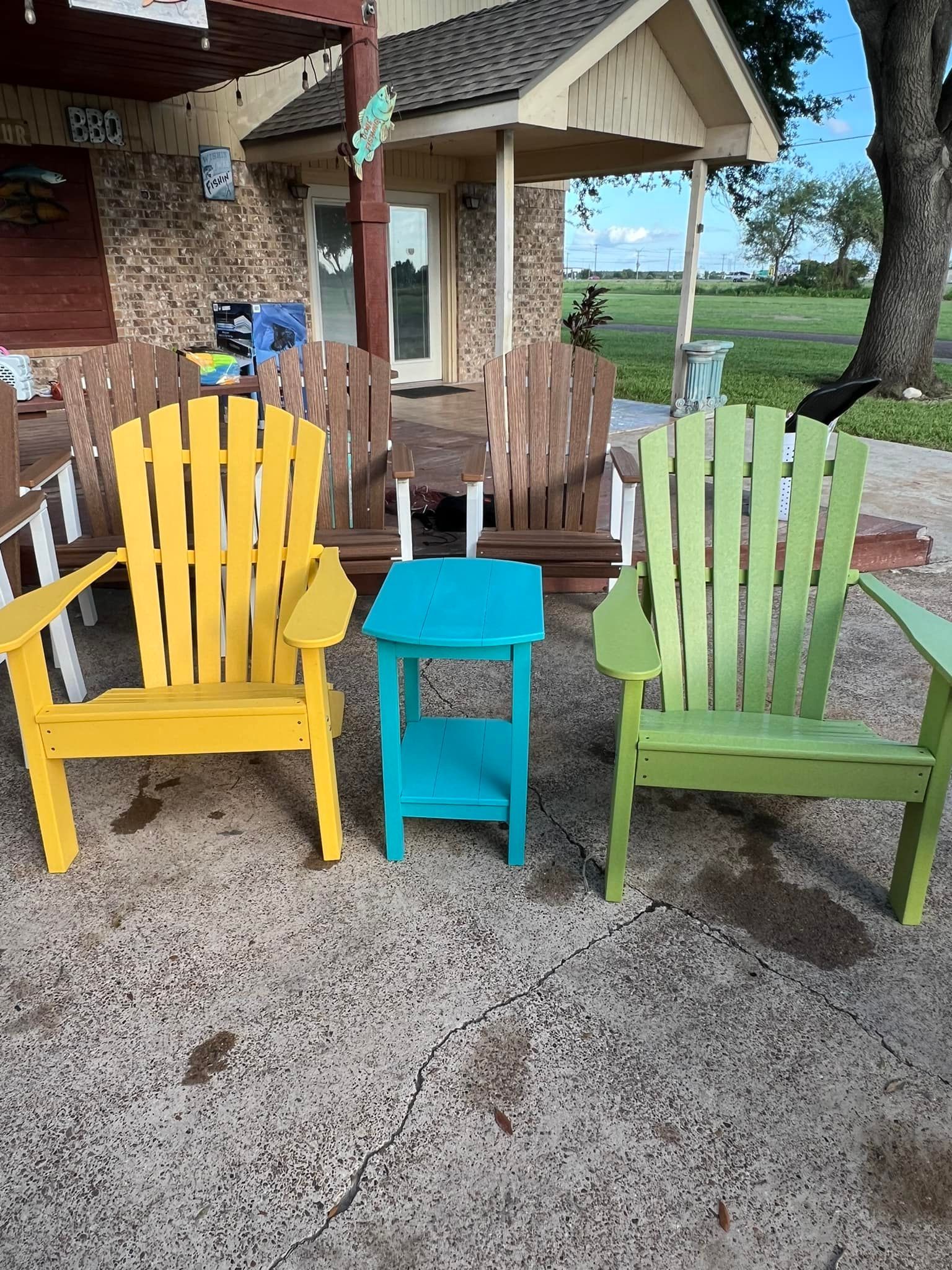 Three adirondack chairs and a table are sitting in front of a house.