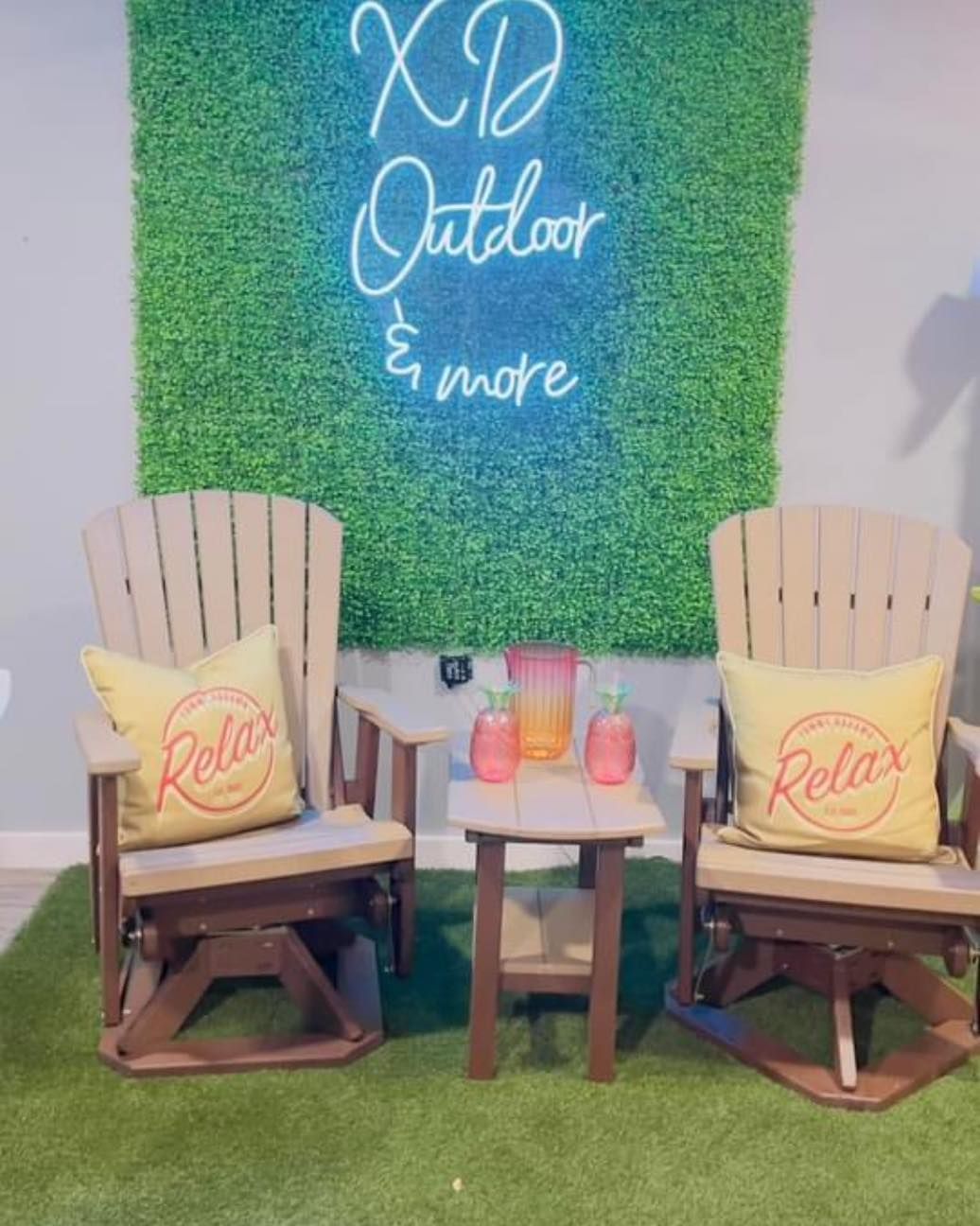 Two chairs and a table in front of a neon sign that says xd outdoor and more.