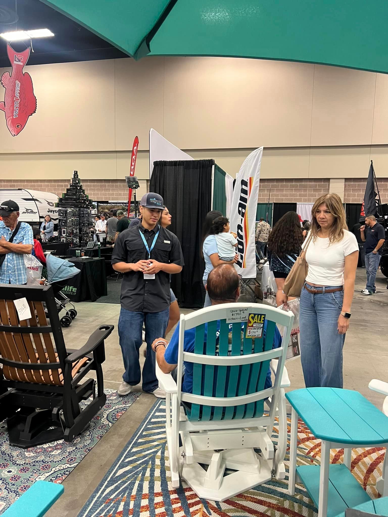 A man is sitting in a blue chair at a convention.
