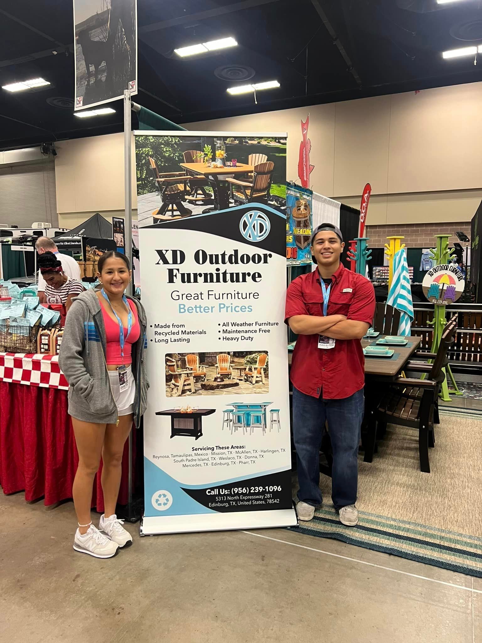 A man and a woman are standing next to a sign at a convention.