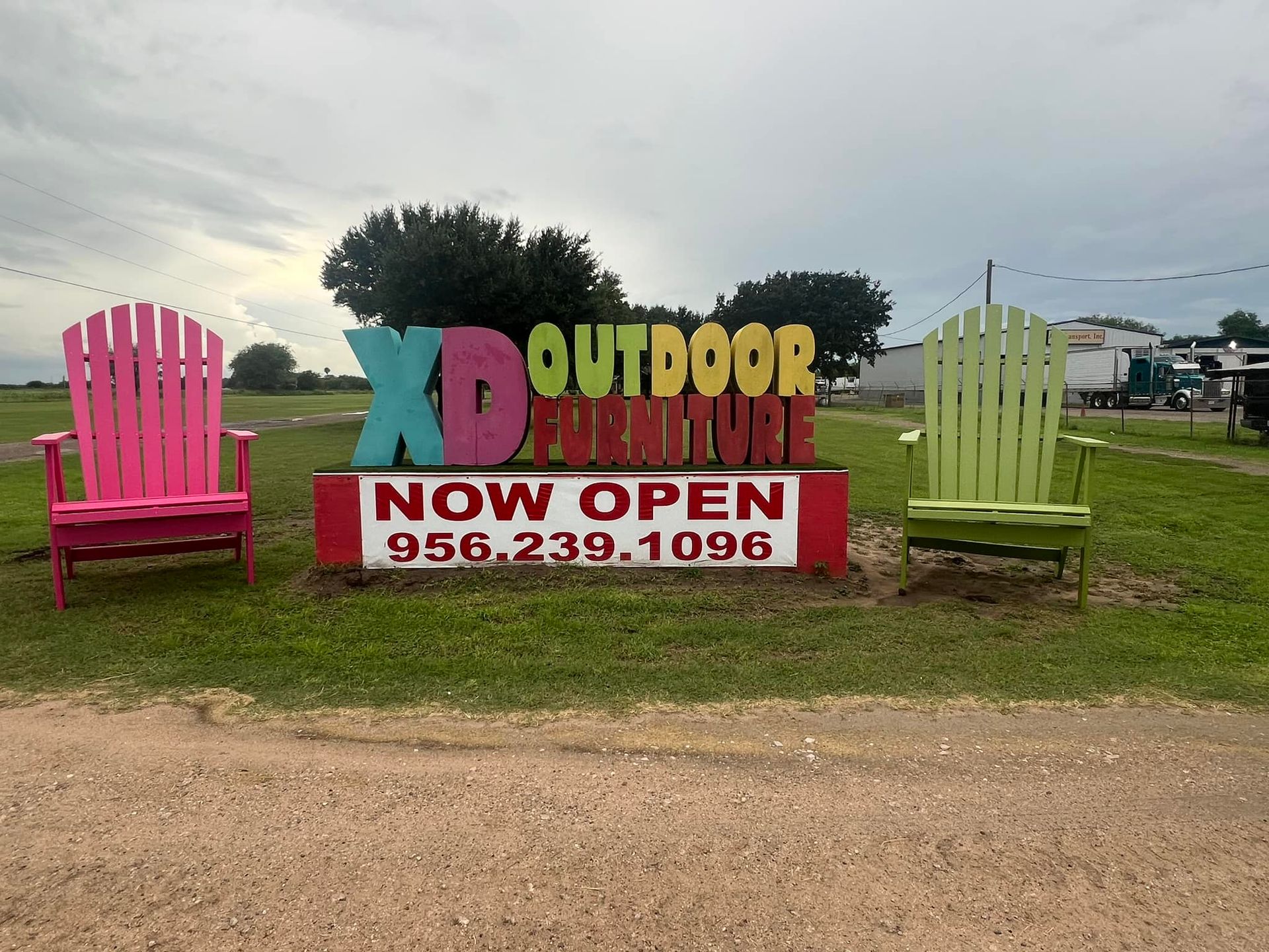 Three adirondack chairs are sitting in front of a sign that says `` outdoor furniture now open ''.