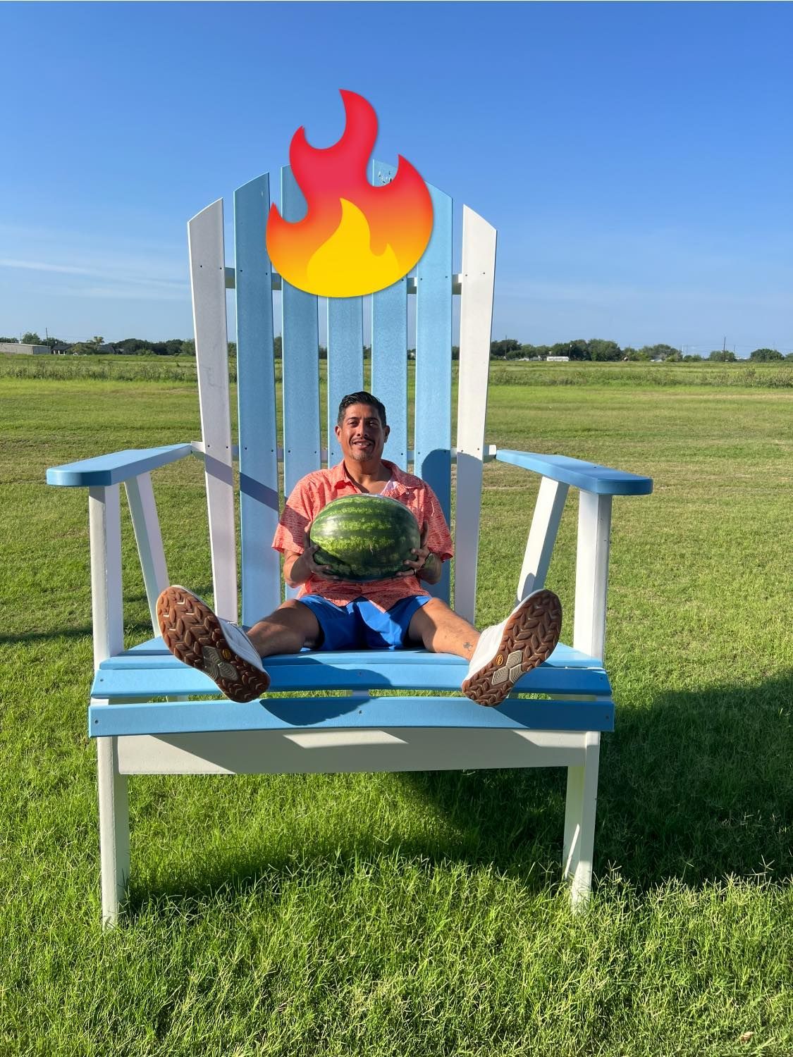 A man is sitting in an adirondack chair holding a watermelon.