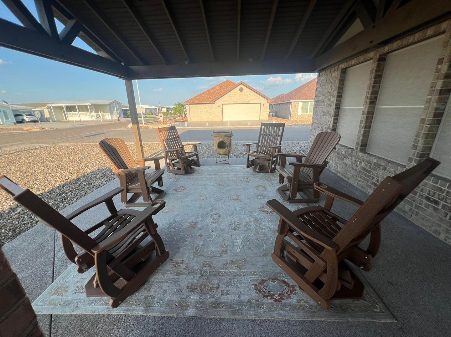 A group of rocking chairs are sitting under a covered porch.