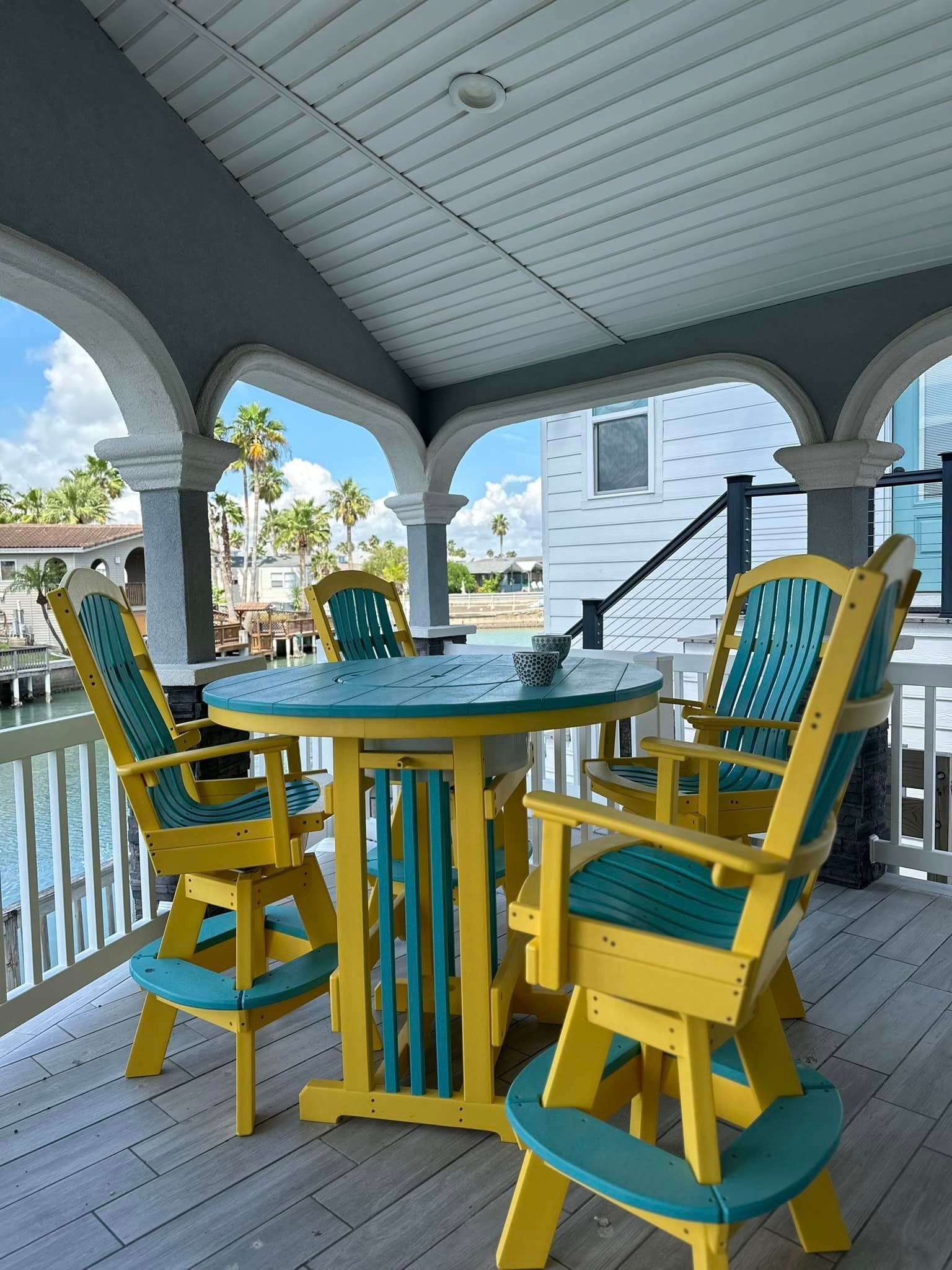 There is a table and chairs on the porch with a view of the water.