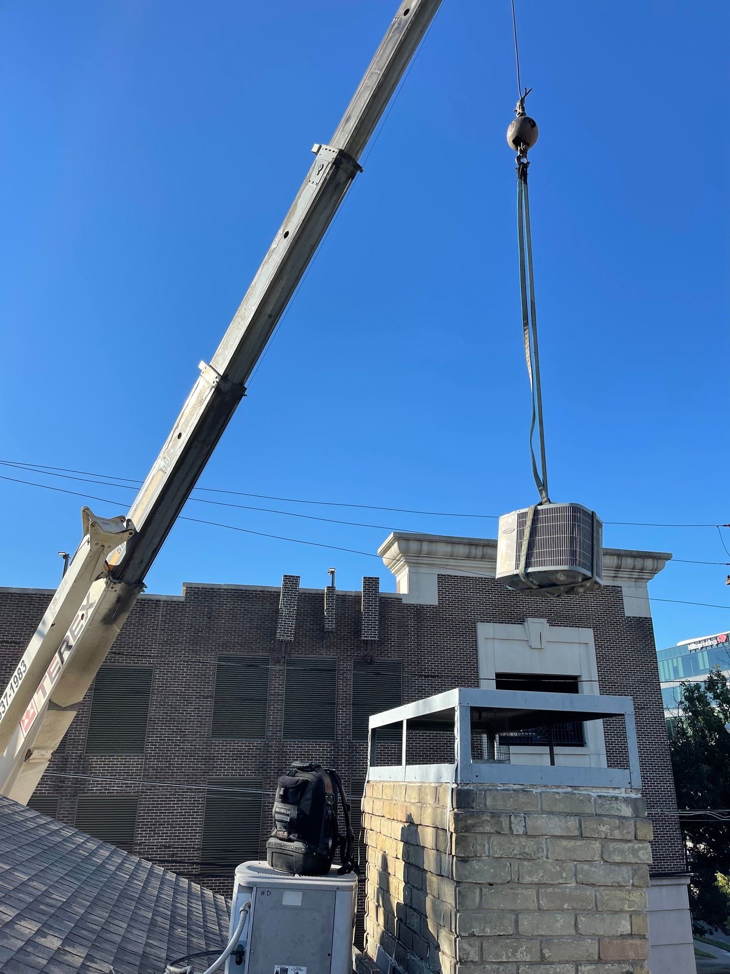 a crane is lifting a brick chimney on top of a building .