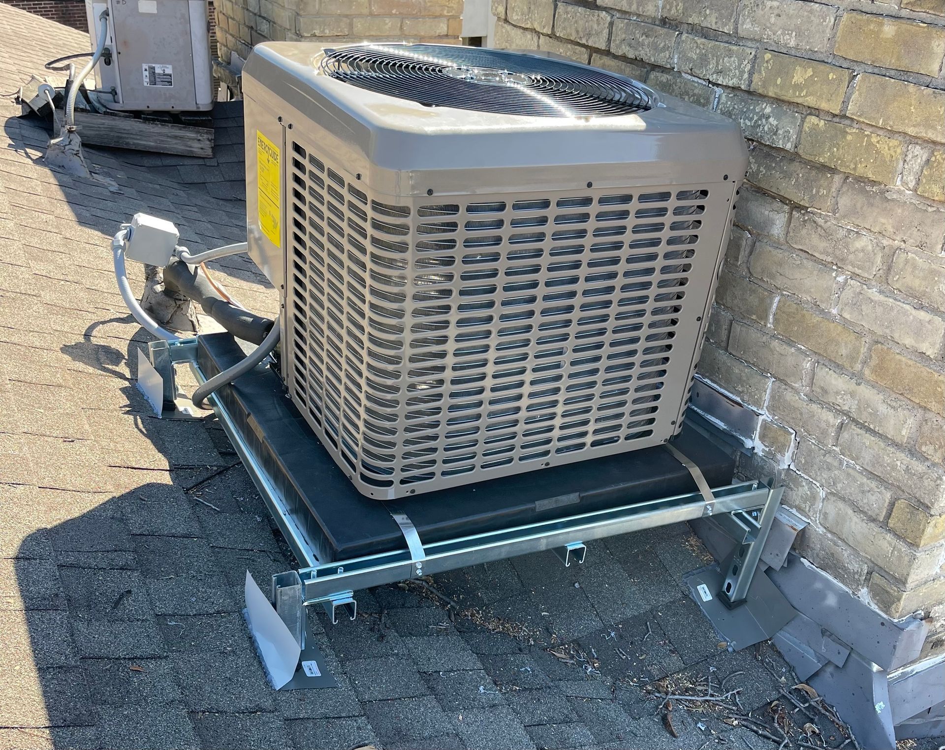 an air conditioner is sitting on top of a metal stand next to a brick wall .