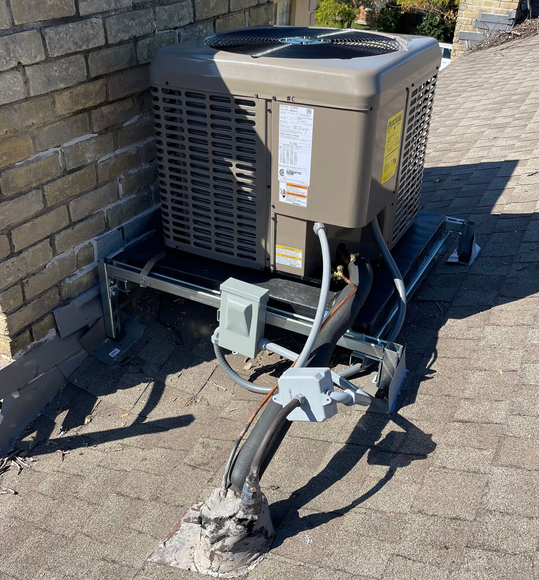 an air conditioner is sitting on top of a concrete platform next to a brick wall .