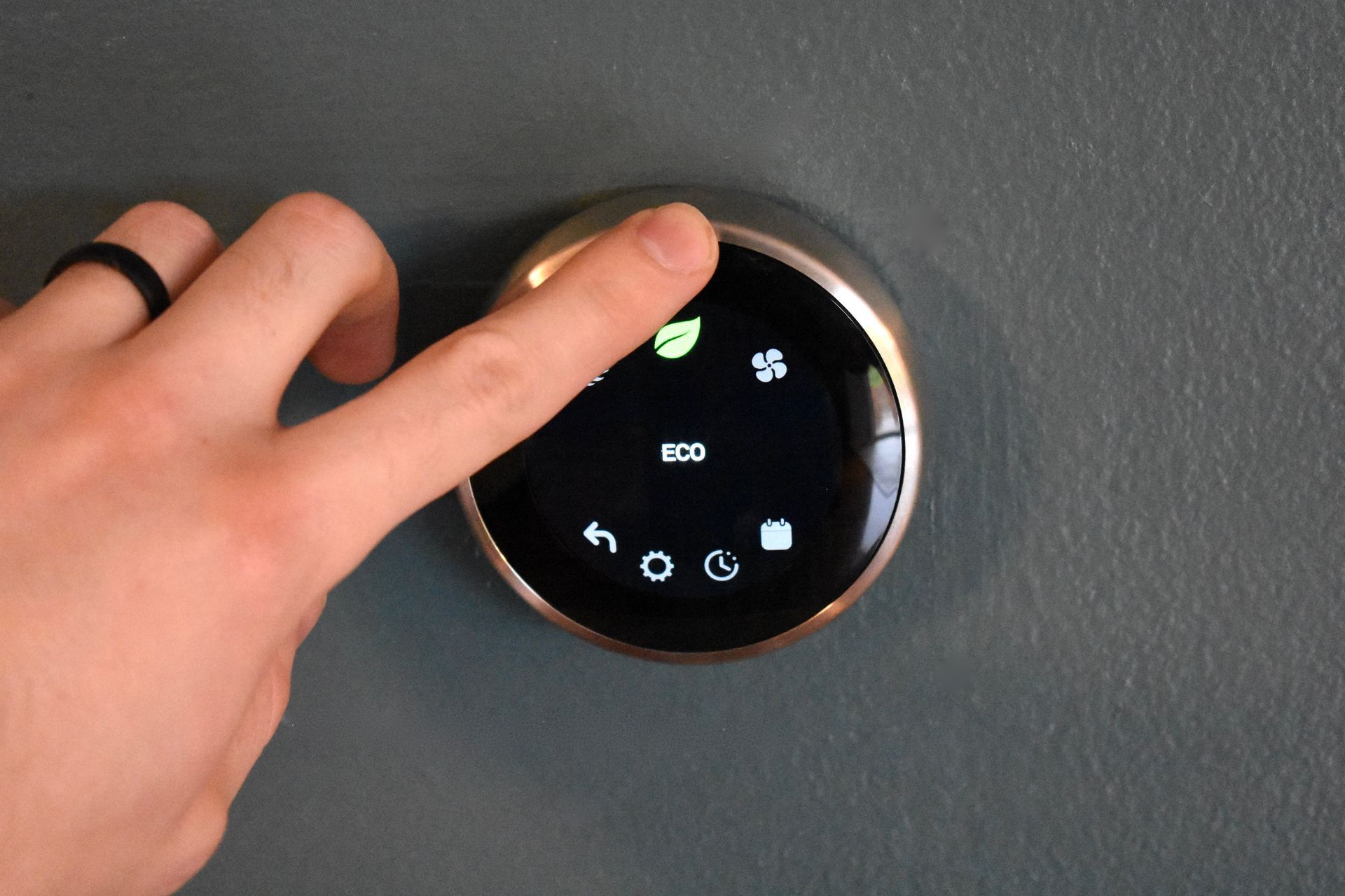 a person is pressing a button on a thermostat .