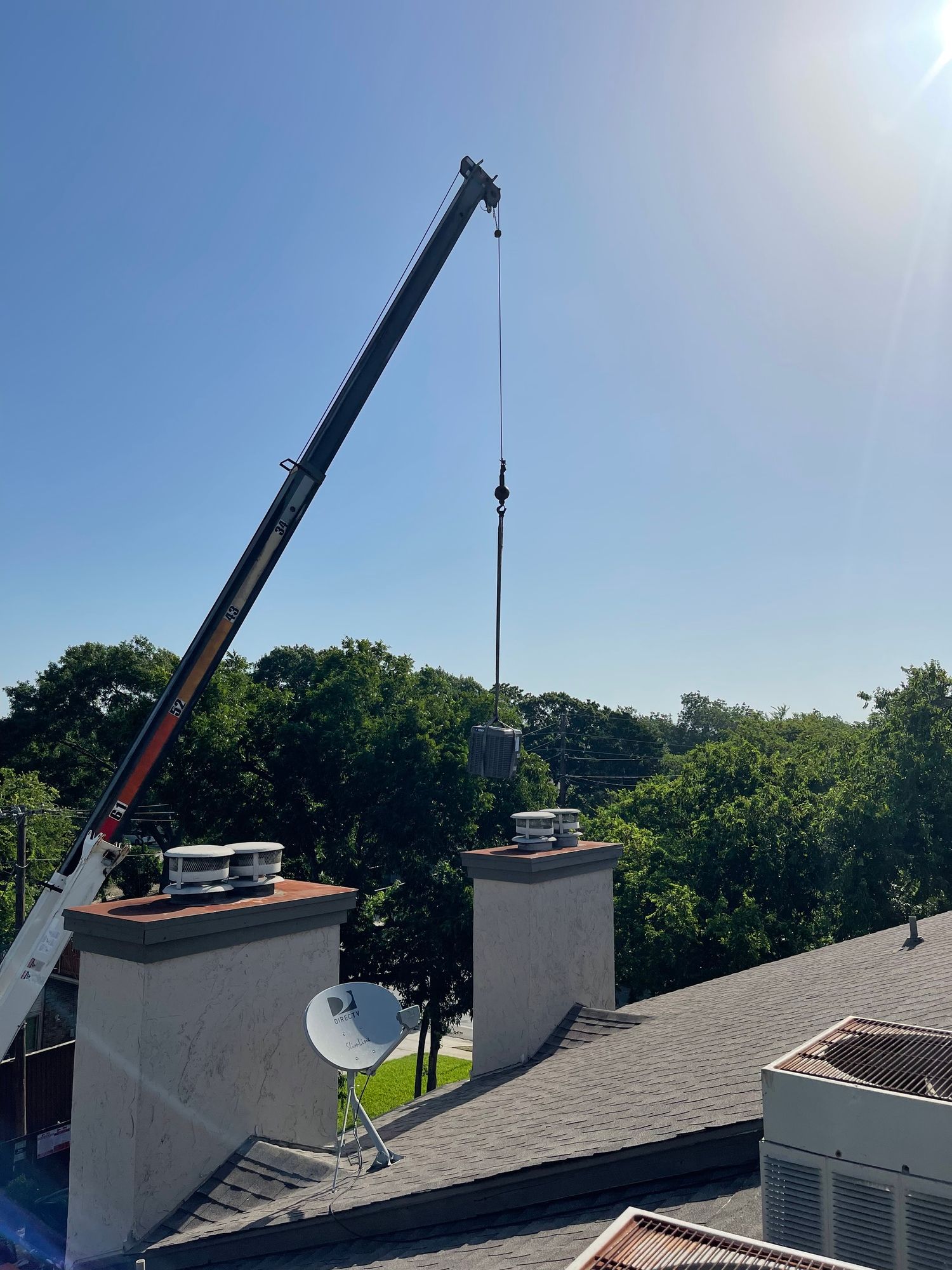 a crane is lifting a chimney on top of a roof