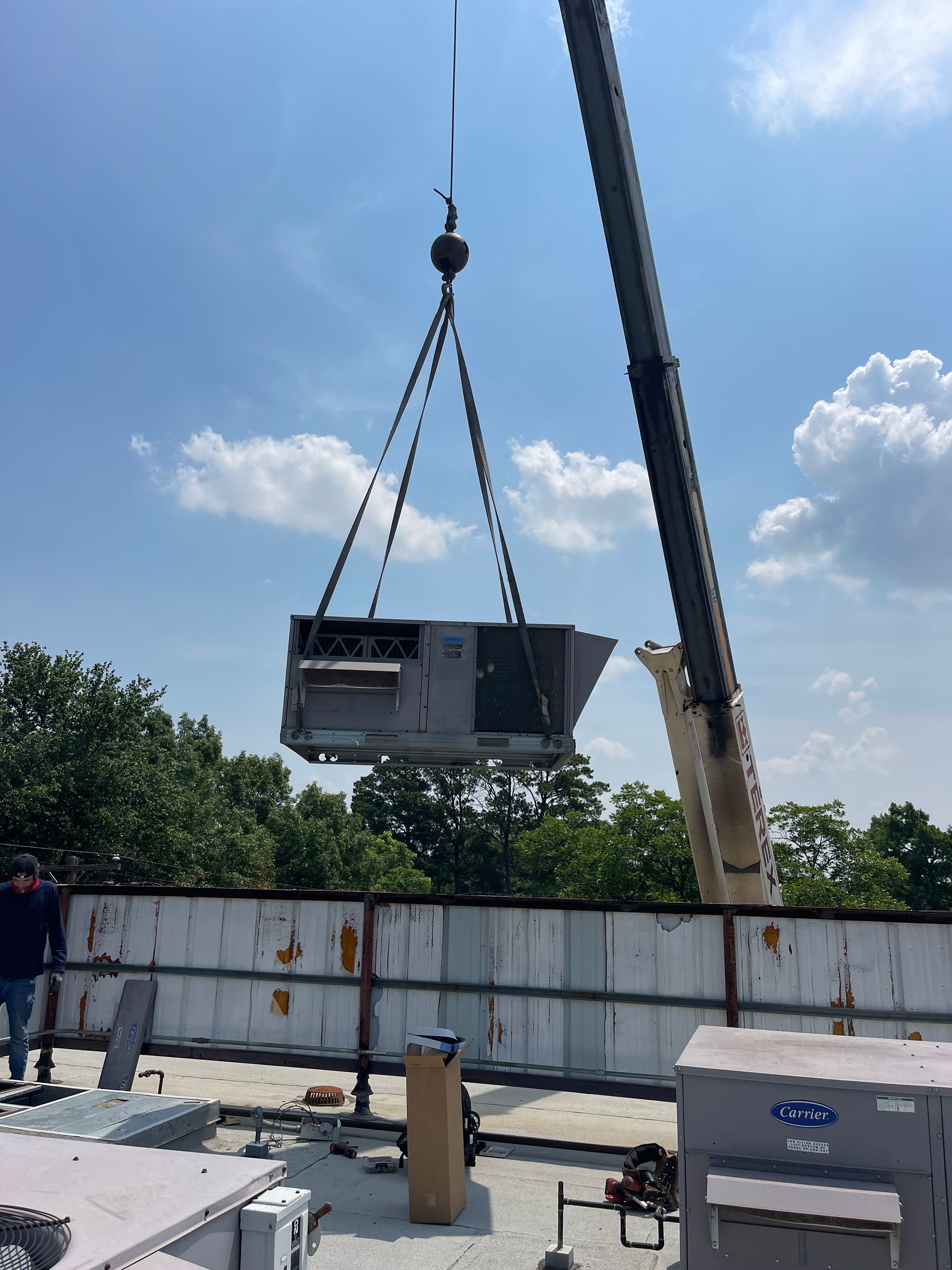 a crane is lifting an air conditioner on top of a building