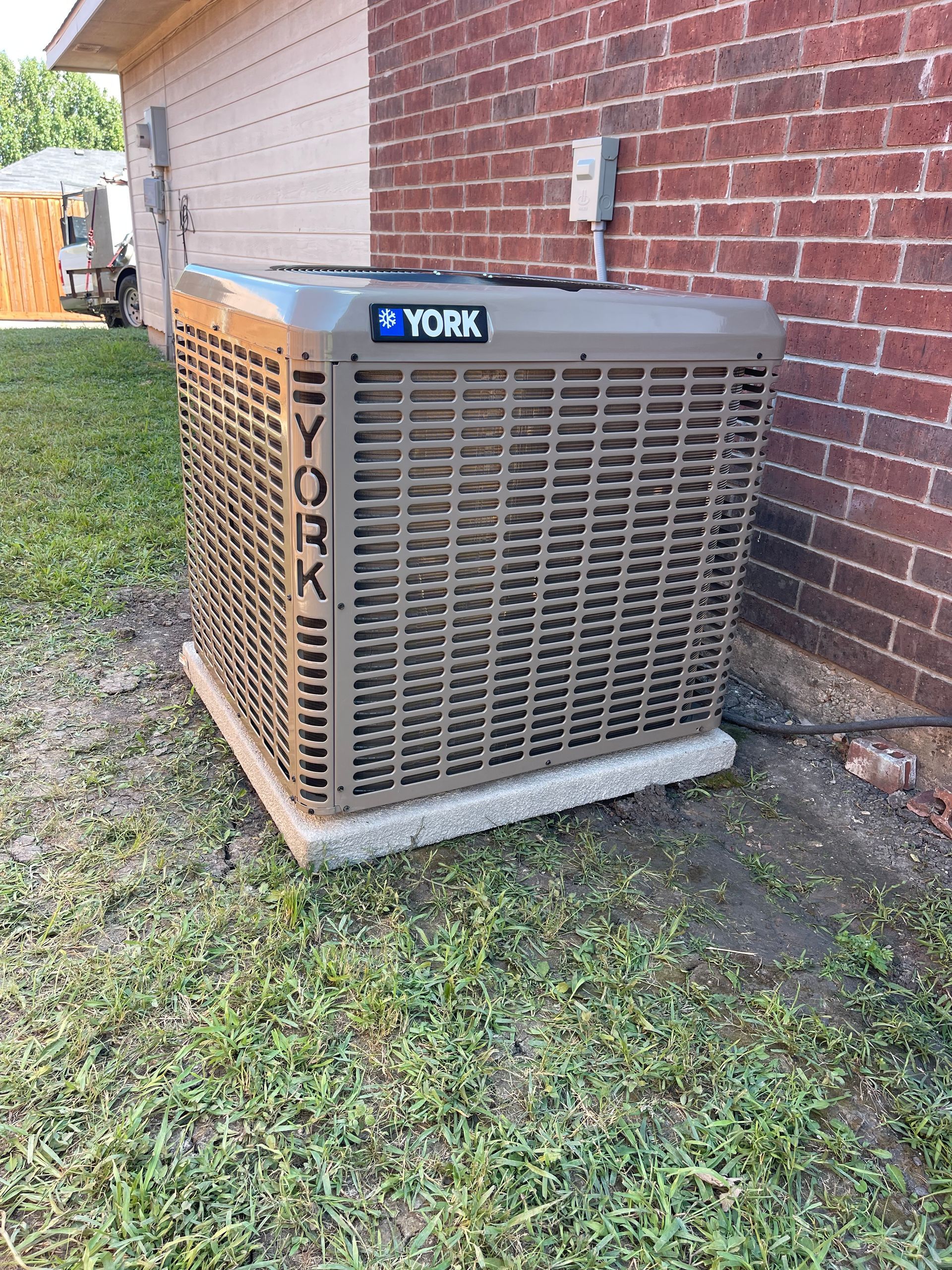 A york air conditioner is sitting outside of a brick building.