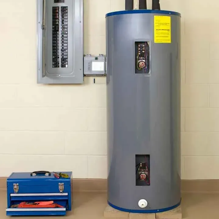 Electric water heater and electrical panel in a room with a toolbox nearby.