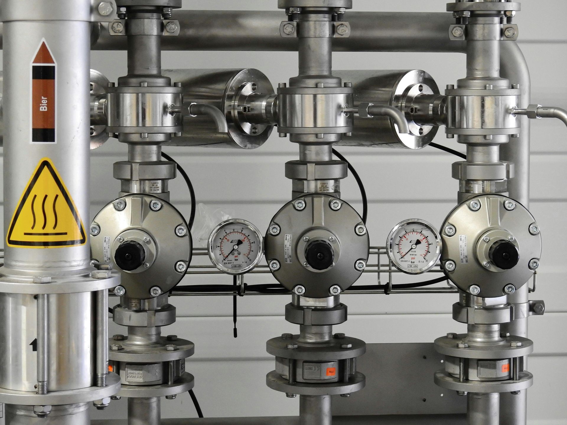 Industrial piping system with valves, gauges, and warning signs.