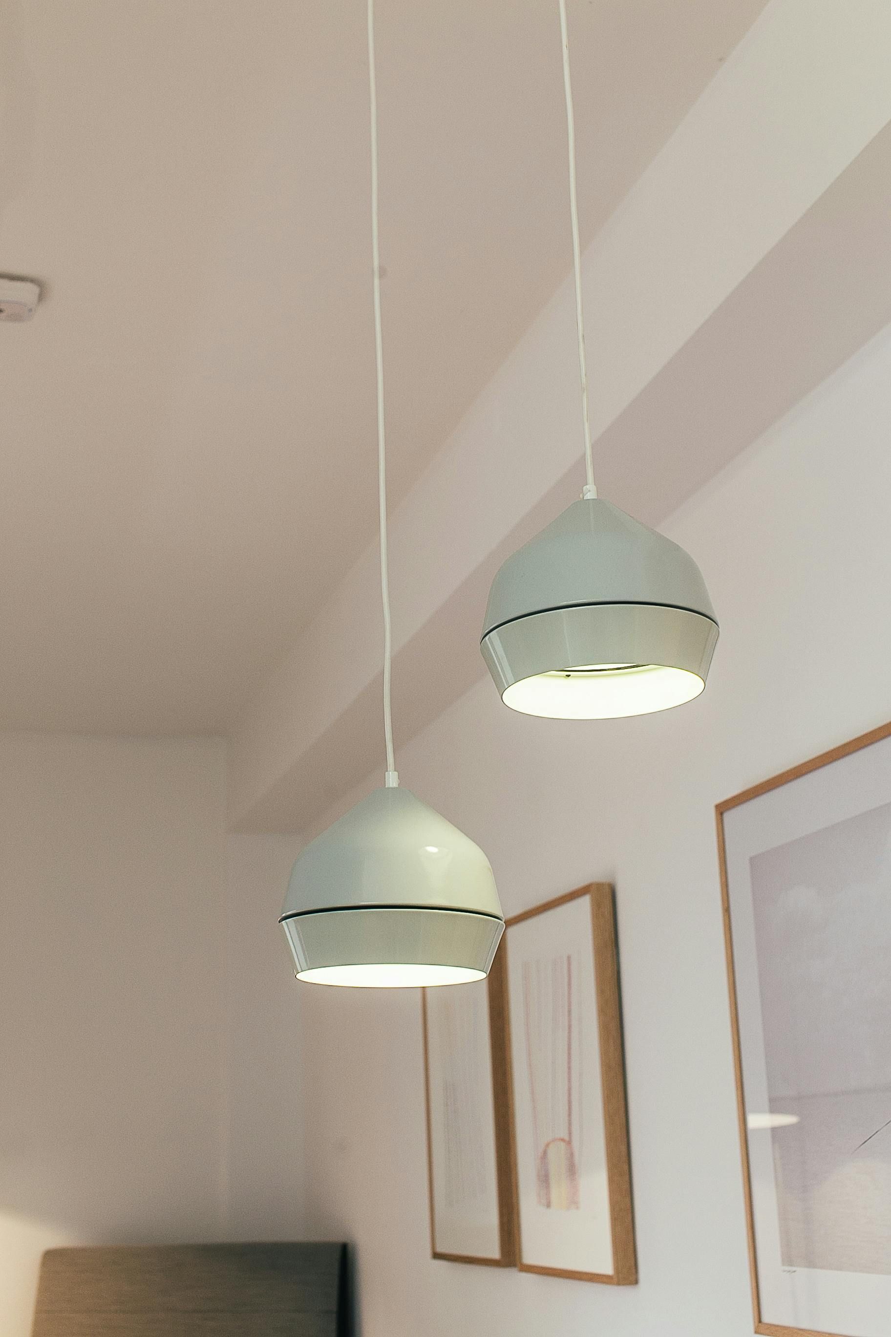 Two pendant lights hanging from a white ceiling, illuminating the room below.